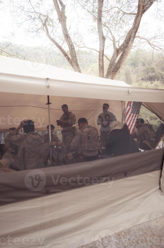 Group of soldiers in camouflage uniforms hold weapons in a field tent, Plan and prepare for combat training. photo