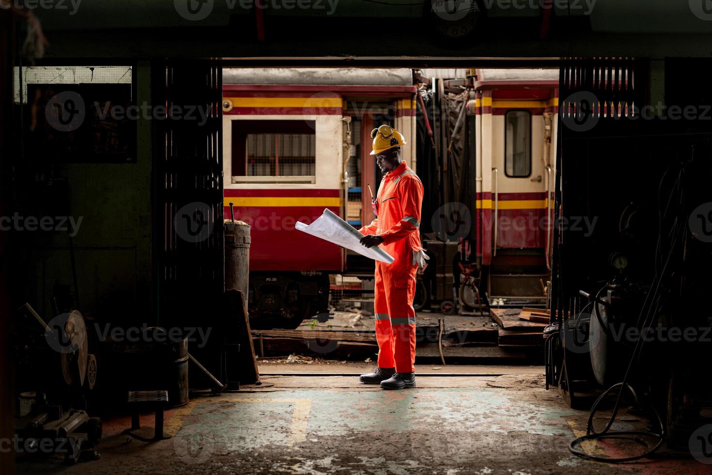 Portrait of railway technician worker in safety vest and helmet working with blueprint at train repair station photo