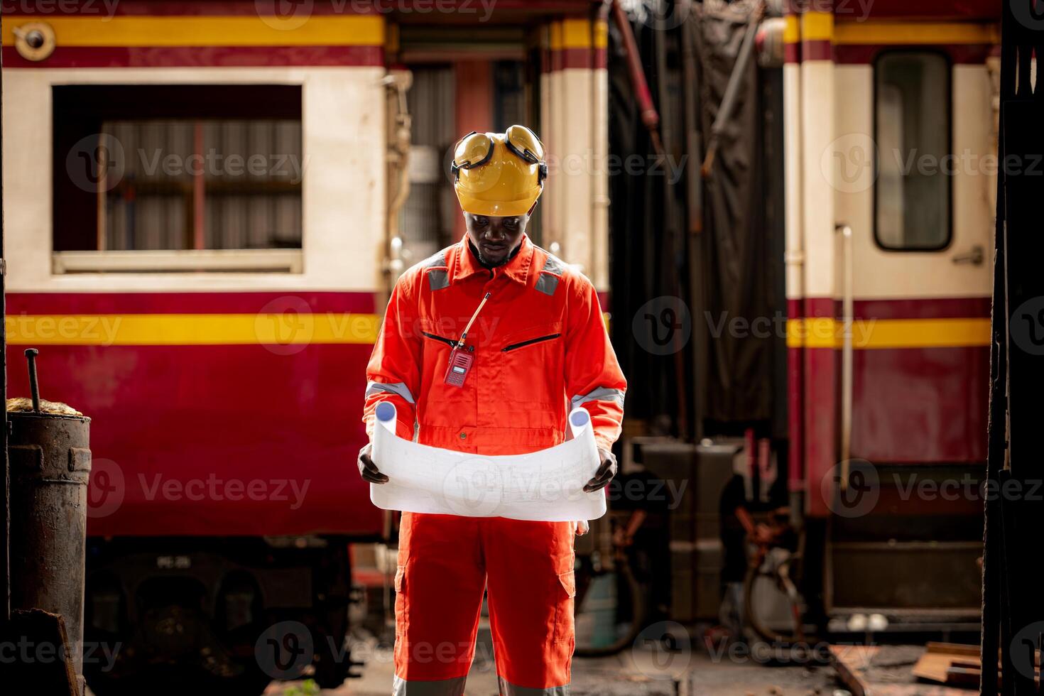 Portrait of railway technician worker in safety vest and helmet working with blueprint at train repair station photo