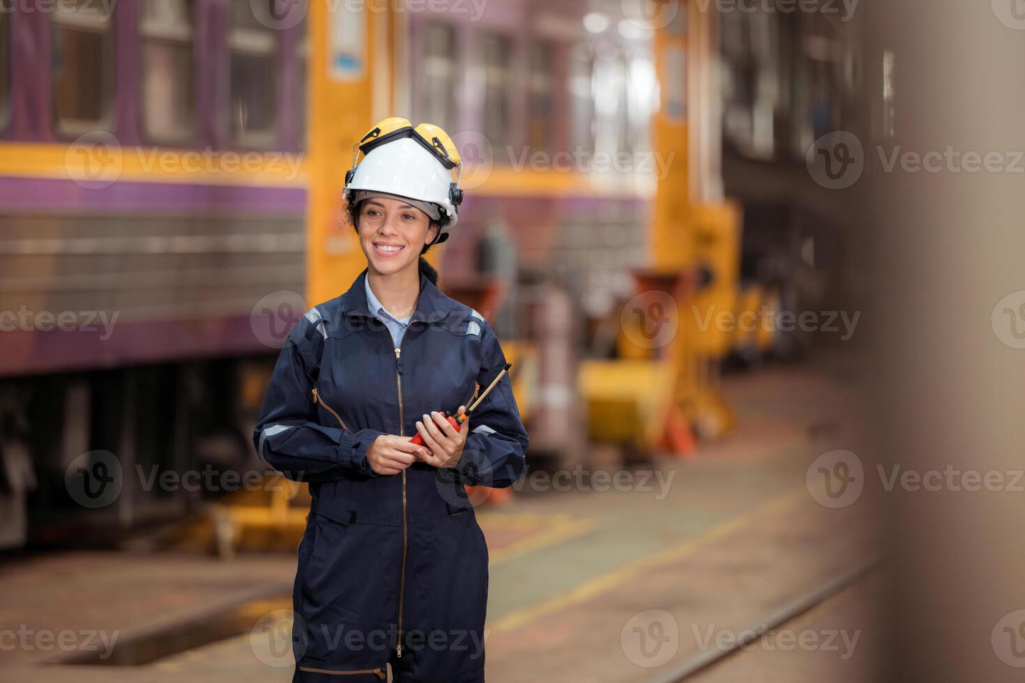 Portrait of railway technician worker in safety vest and helmet working and using a walkie talkie at train repair station photo