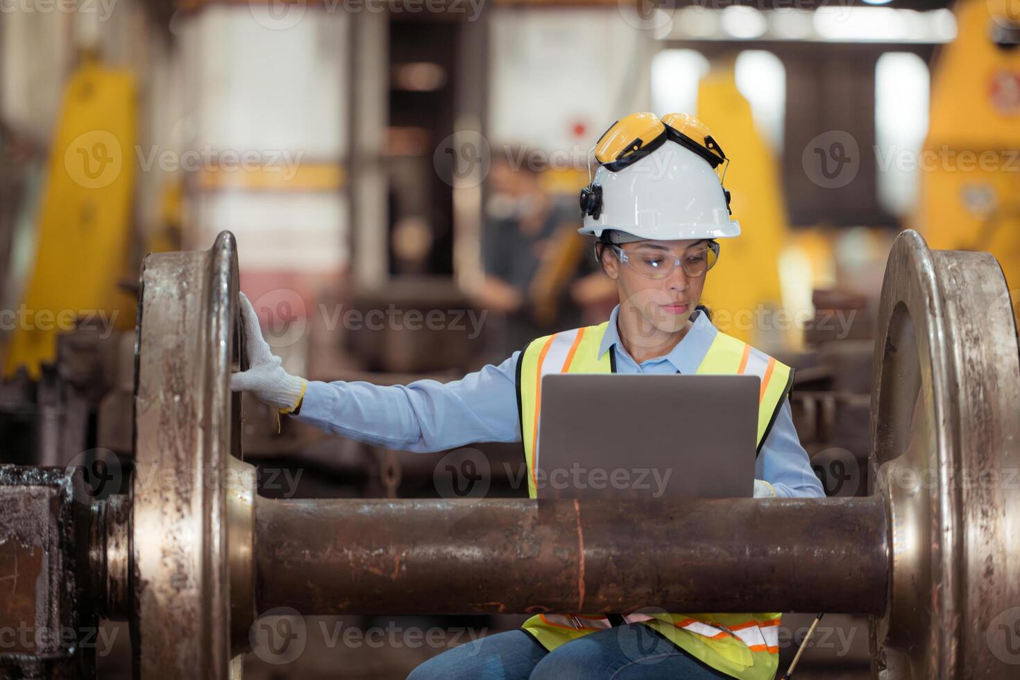 Railway technician in uniform and helmet inspect the train wheels removed from the locomotives in the train workshop. photo