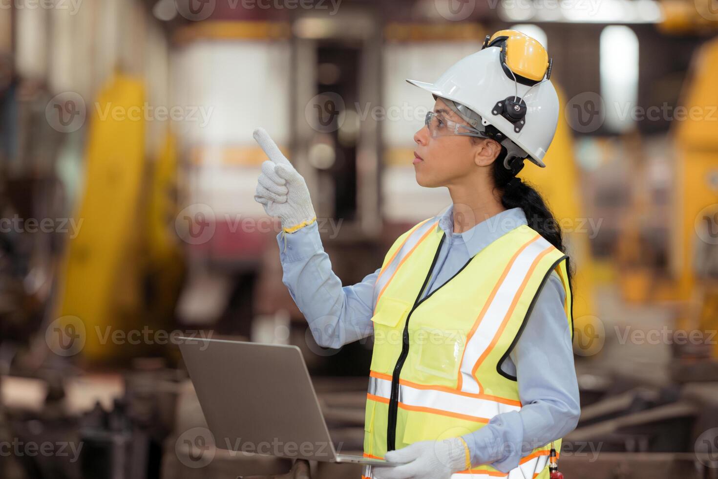 Portrait of railway technician worker in safety vest and helmet working with blueprint at train repair station photo