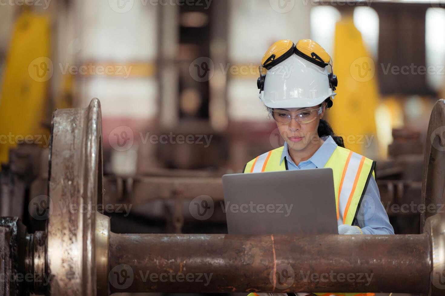 Railway technician in uniform and helmet inspect the train wheels removed from the locomotives in the train workshop. photo