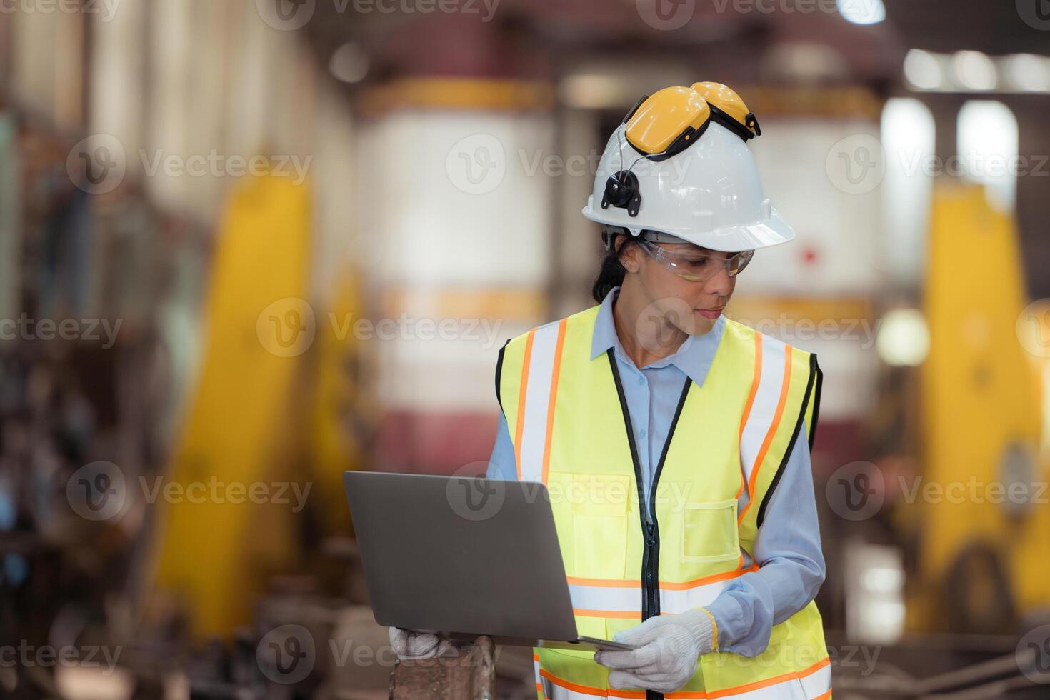 Portrait of railway technician worker in safety vest and helmet working with blueprint at train repair station photo