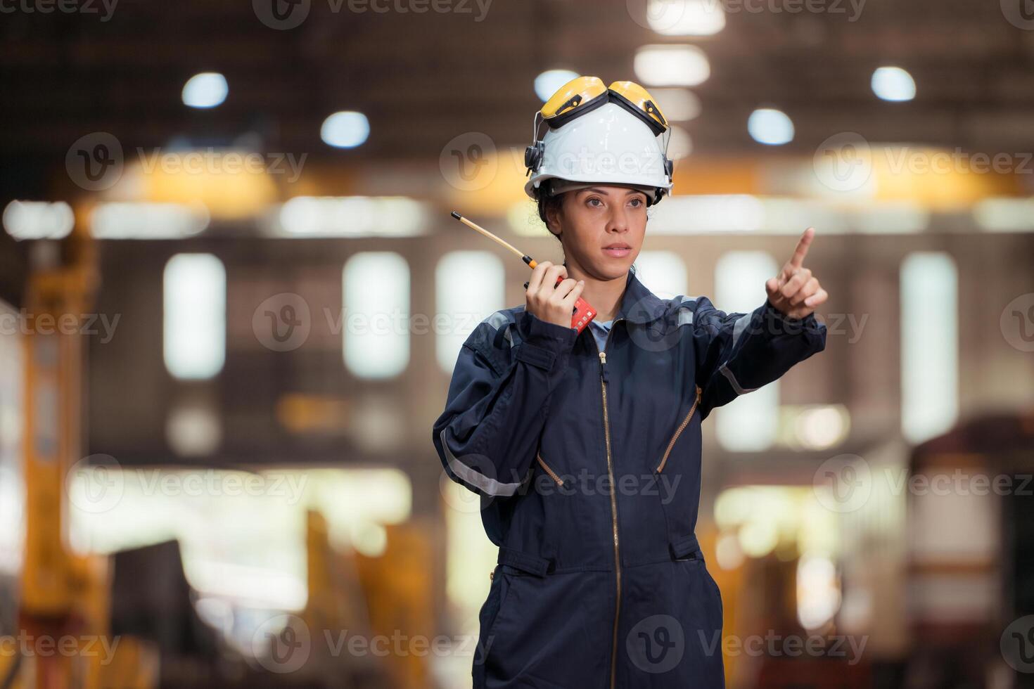 Portrait of railway technician worker in safety vest and helmet working and using a walkie talkie at train repair station photo