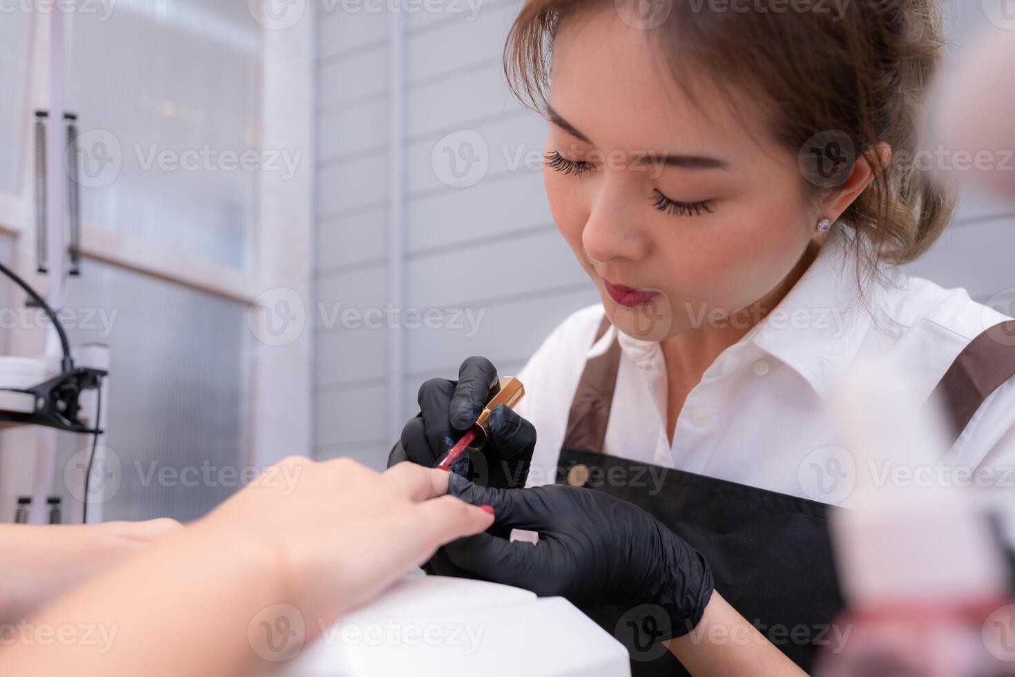 A nail technician is painting the nails of a customer. photo
