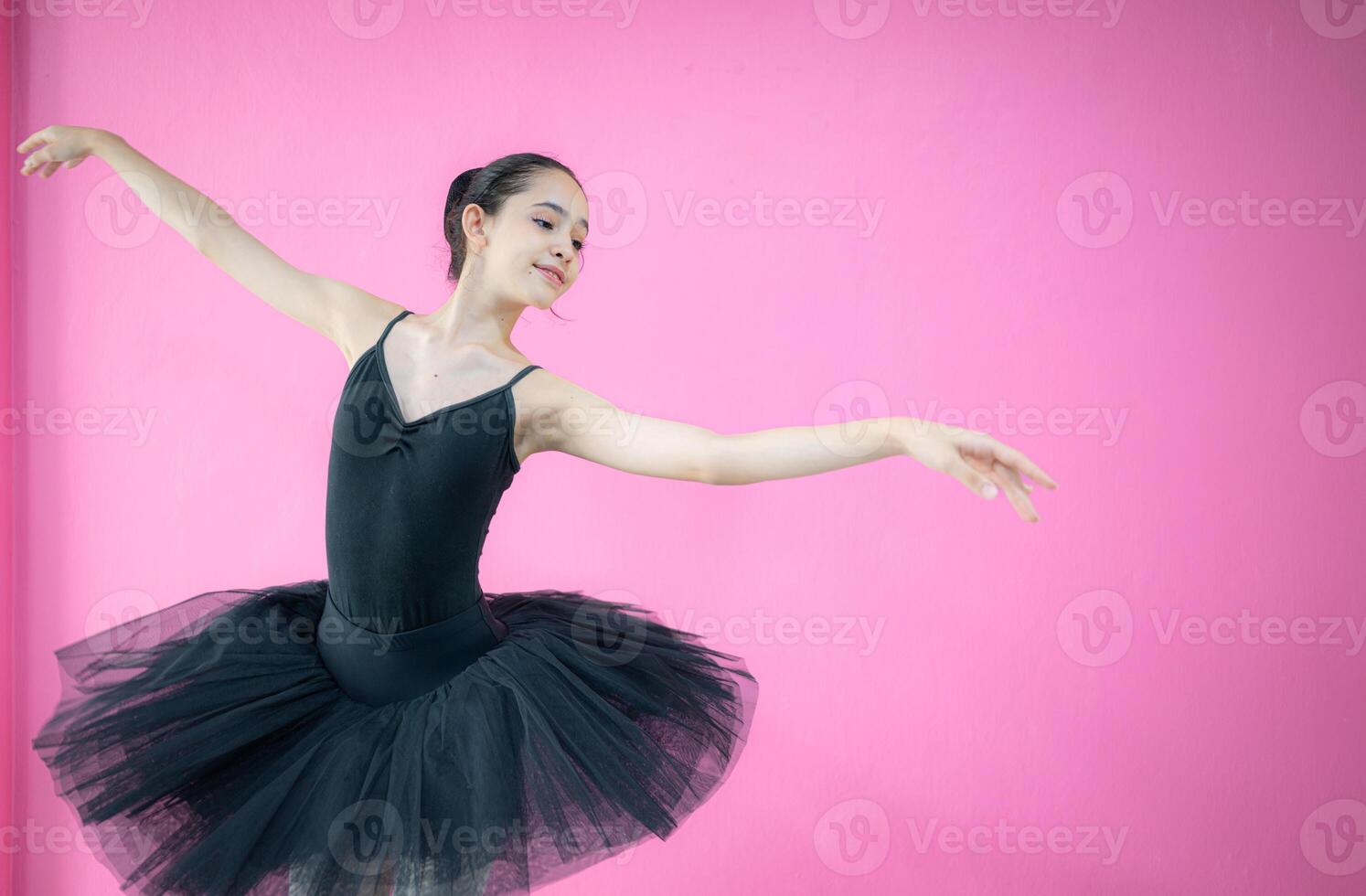 A girl ballet student practices ballet dancing at home with a white background photo