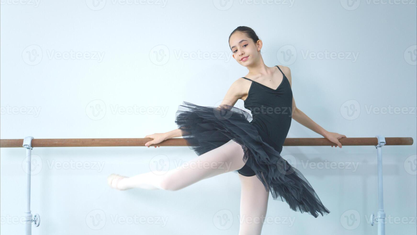 A girl ballet student practices ballet dancing at home with a white background photo