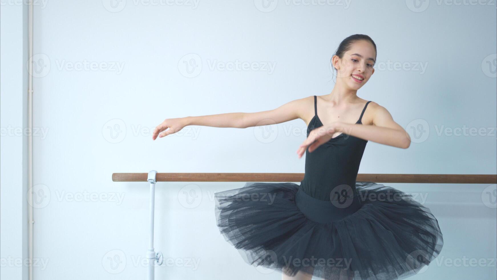 A girl ballet student practices ballet dancing at home with a white background photo