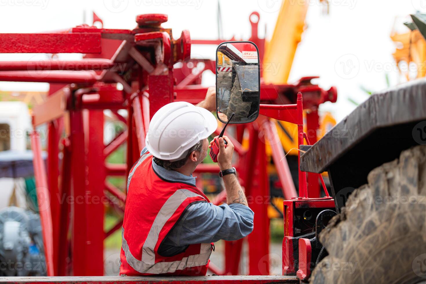 Crane foreman uses walkie-talkie and inspect the construction crane lifting heavy items in the storage warehouse for assembly on the construction site photo