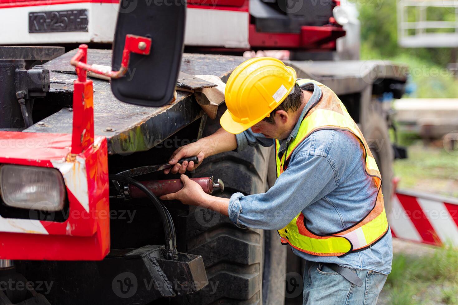 Engineers and technicians grease the wheel axle of a large crane before moving to the construction site photo