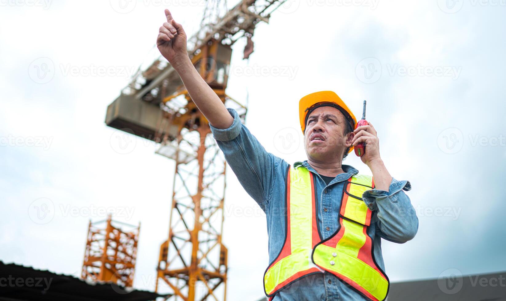Portrait of crane worker uses walkie-talkie communicate with tower crane operators to lift and move objects on building construction sites photo