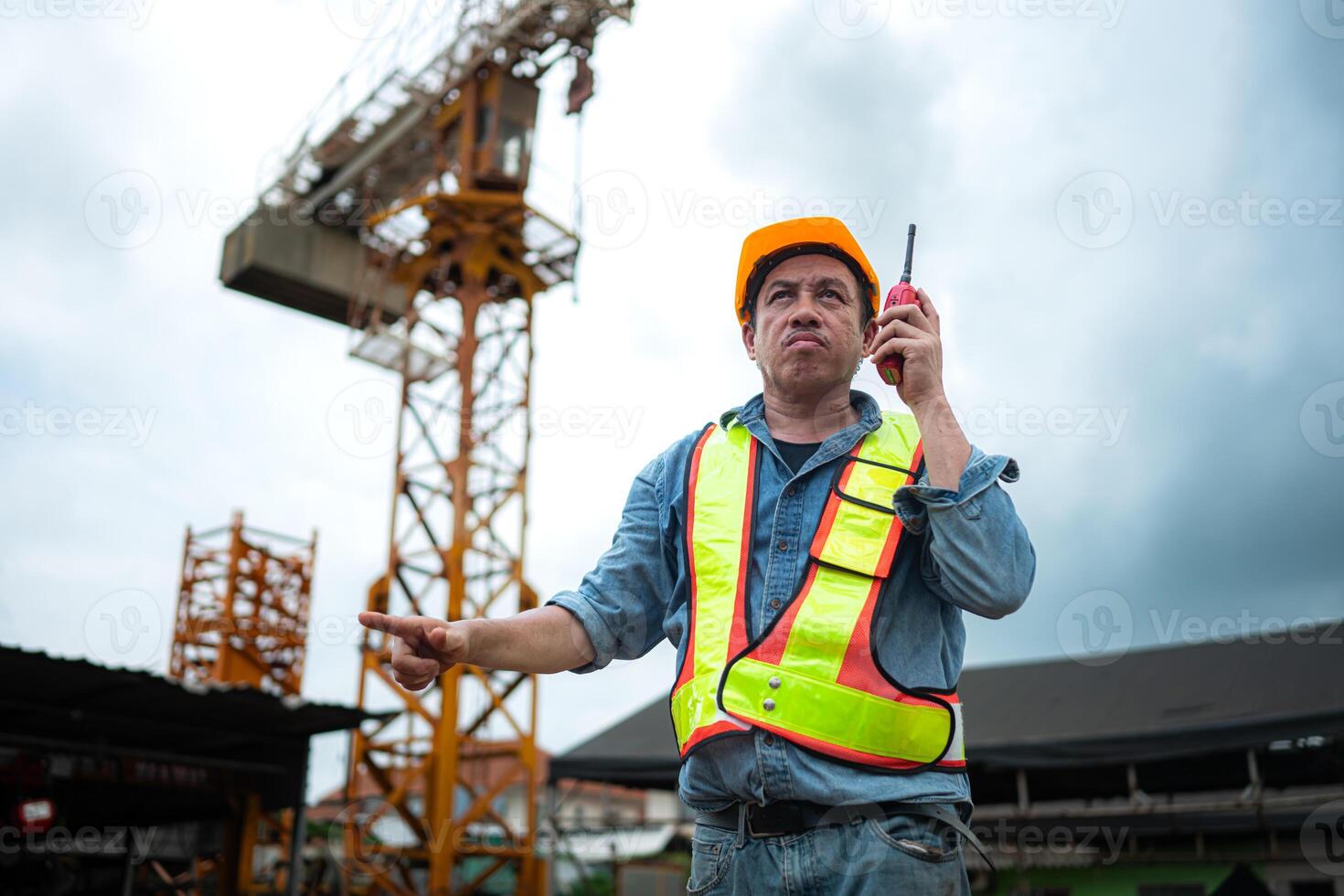 Portrait of crane worker uses walkie-talkie communicate with tower crane operators to lift and move objects on building construction sites photo