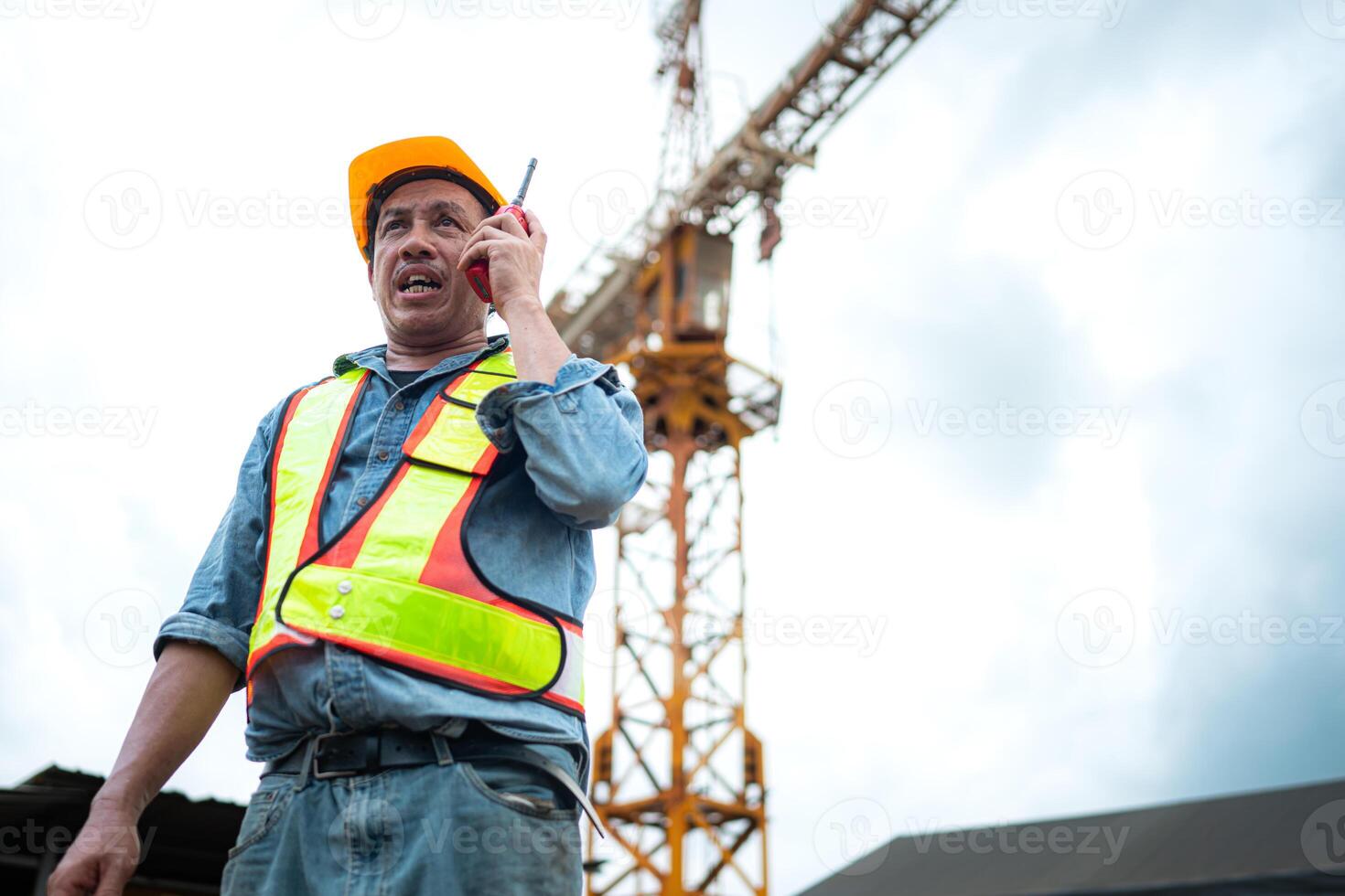 Portrait of crane worker uses walkie-talkie communicate with tower crane operators to lift and move objects on building construction sites photo