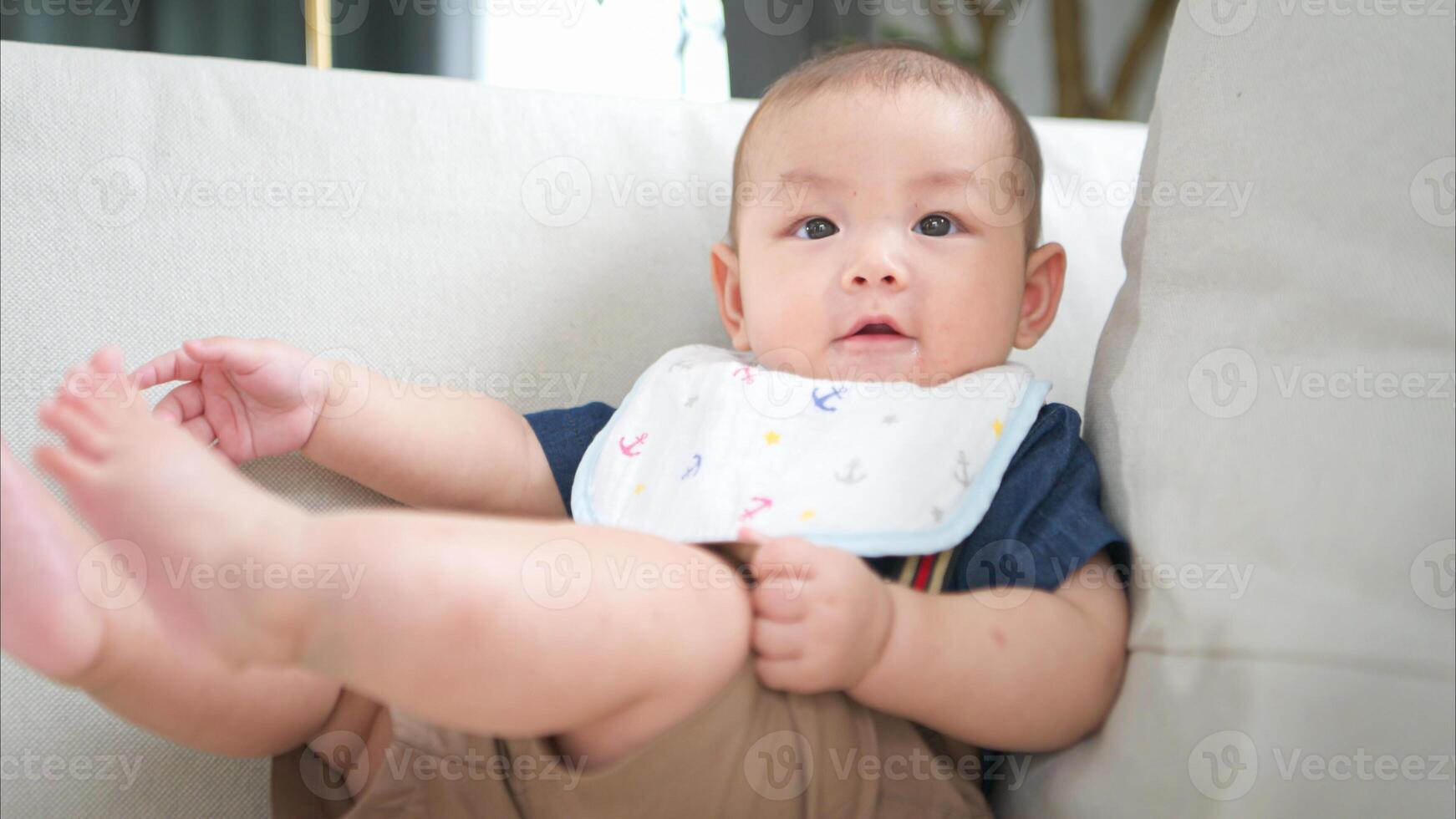 A tiny child sits smiling happily on the couch in the living room photo