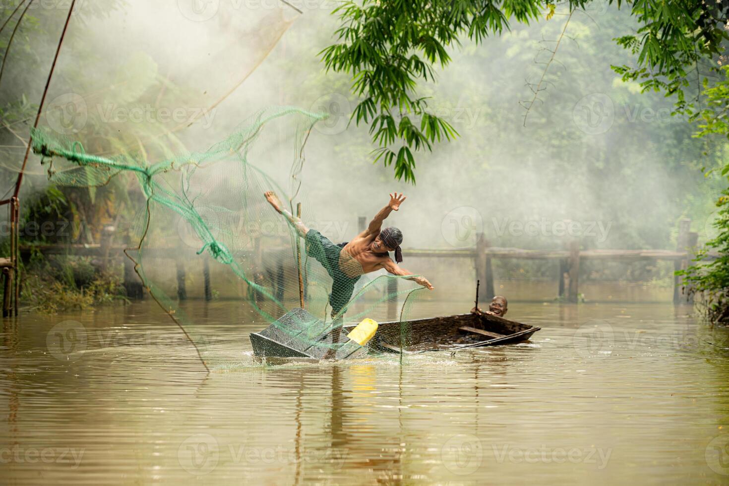 Two farmers on a boat in the river using a fishnet to catch fish photo