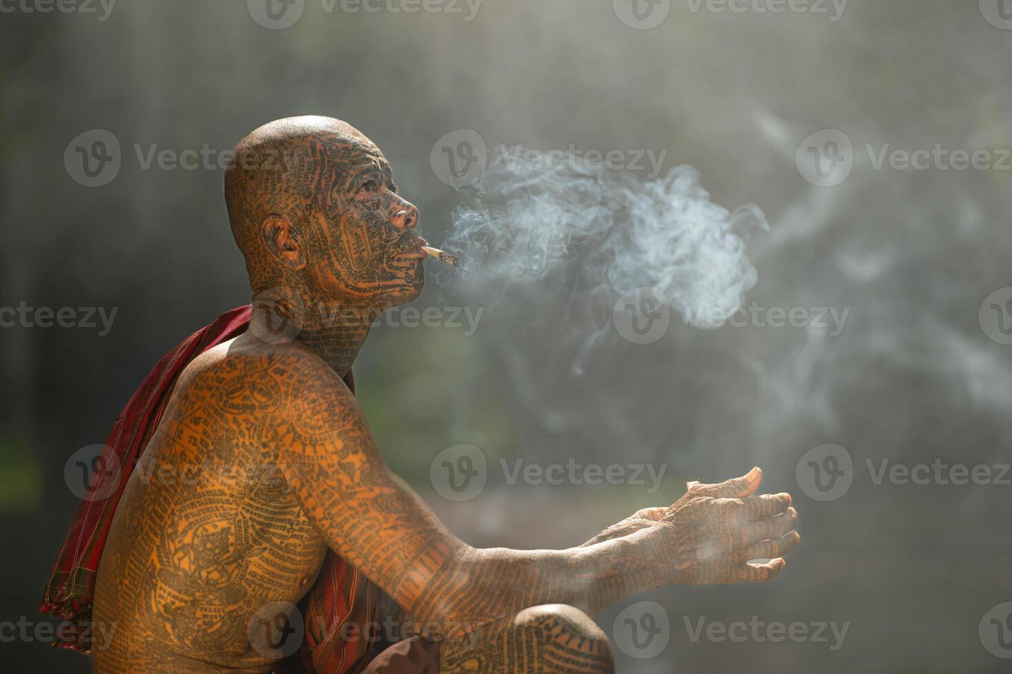 A tattooed elderly man smoking a cigarette in the garden photo