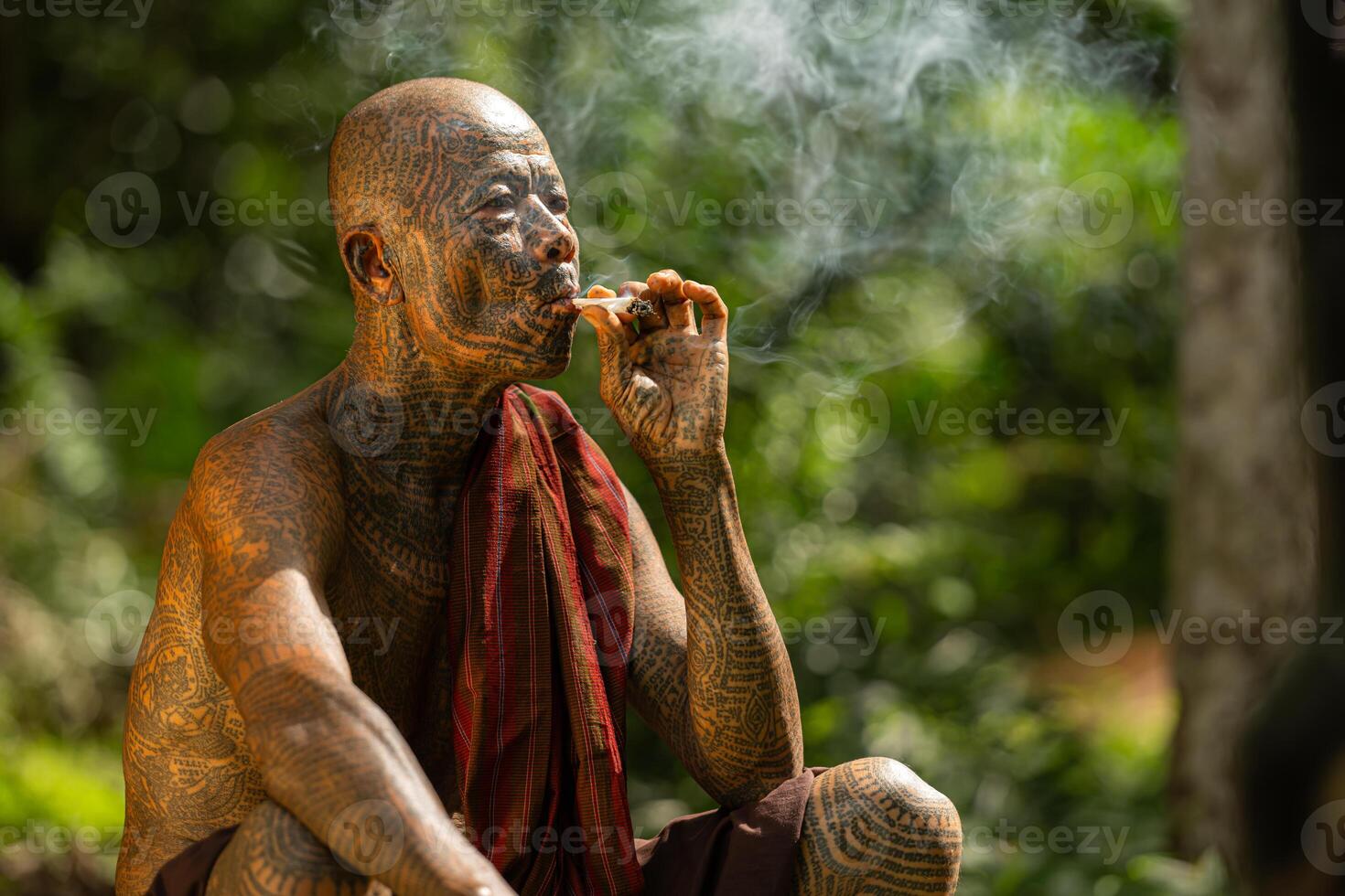 A tattooed elderly man smoking a cigarette in the garden photo