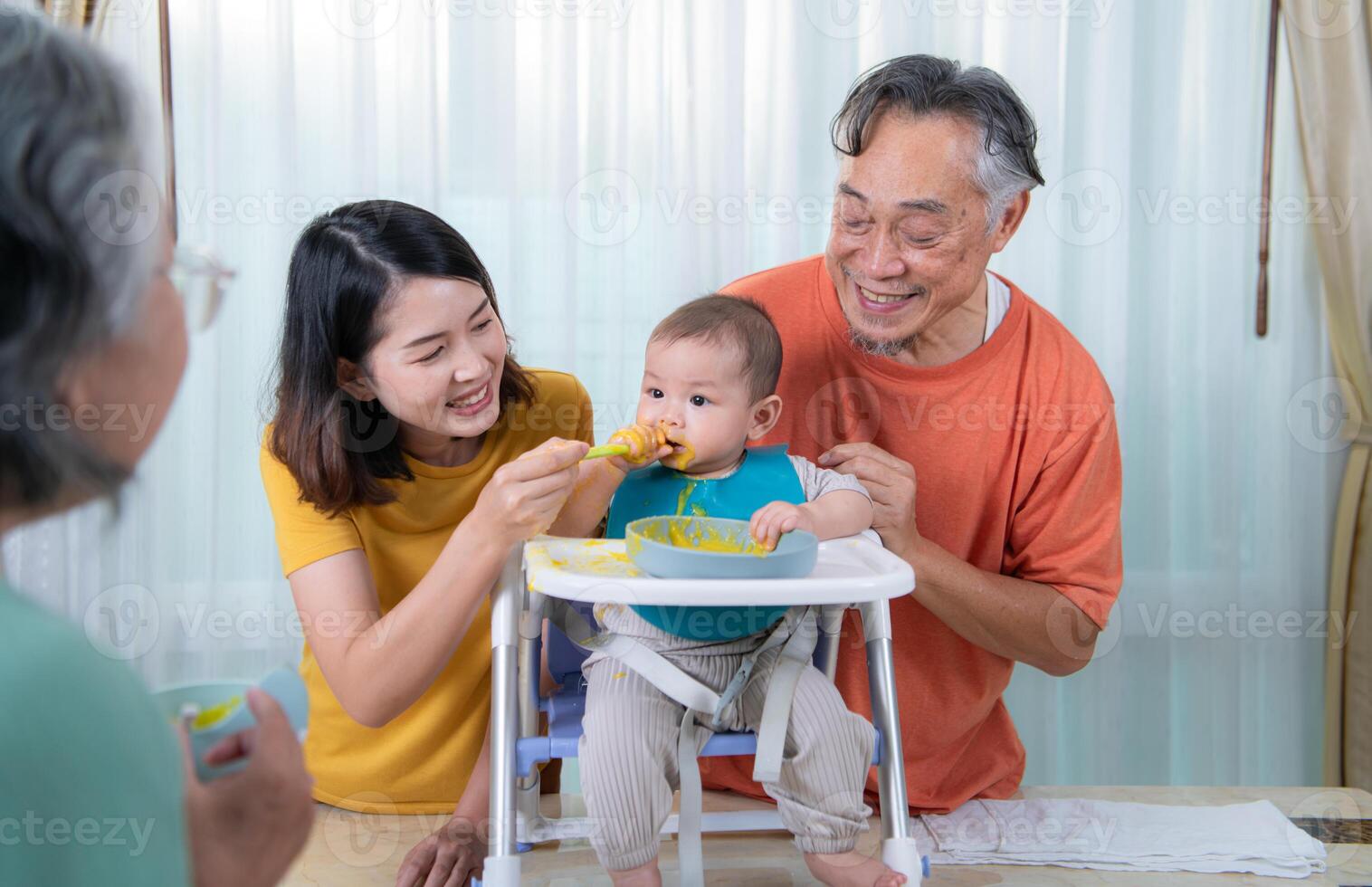 un pequeño niño comiendo su primero comida, padres y abuelos animar emocionado foto