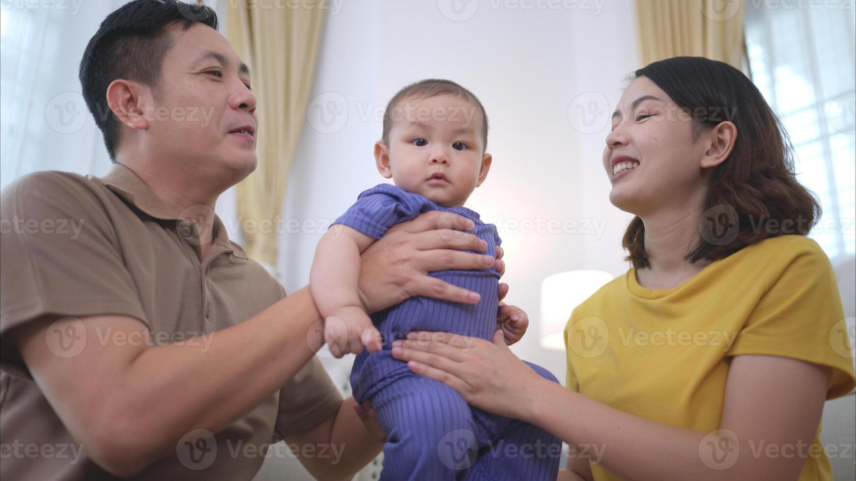 Parents and their little child play happily in the living room of the house photo