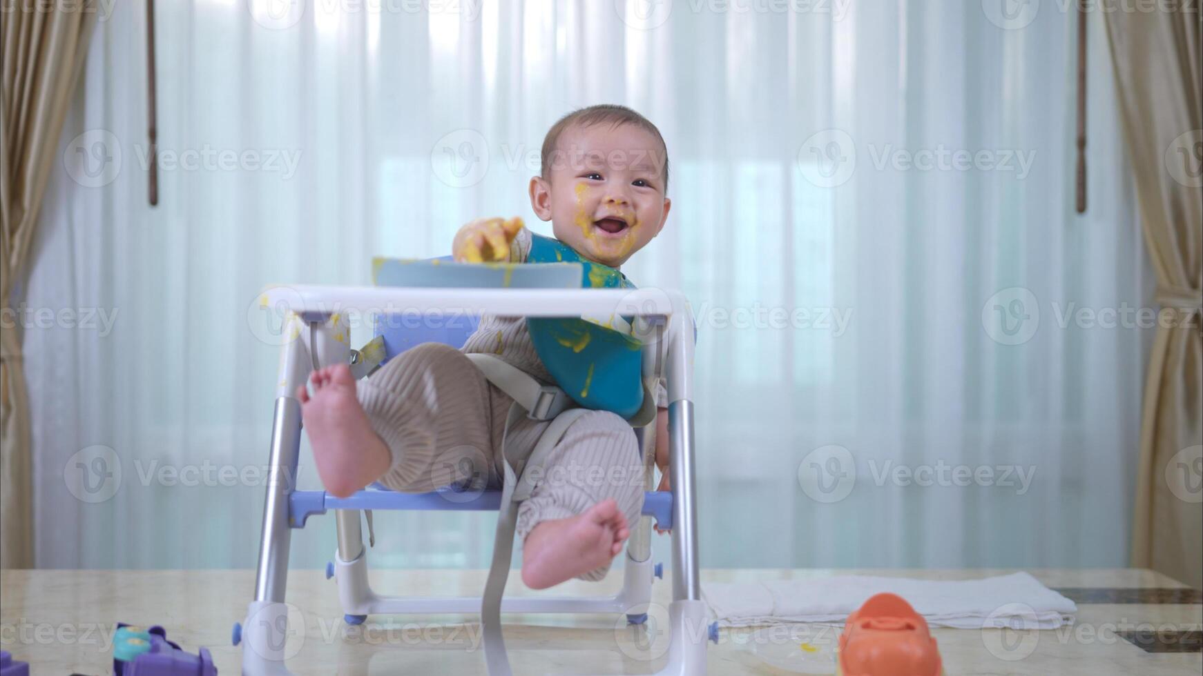 A little child eating his first meal on a high chair for children photo