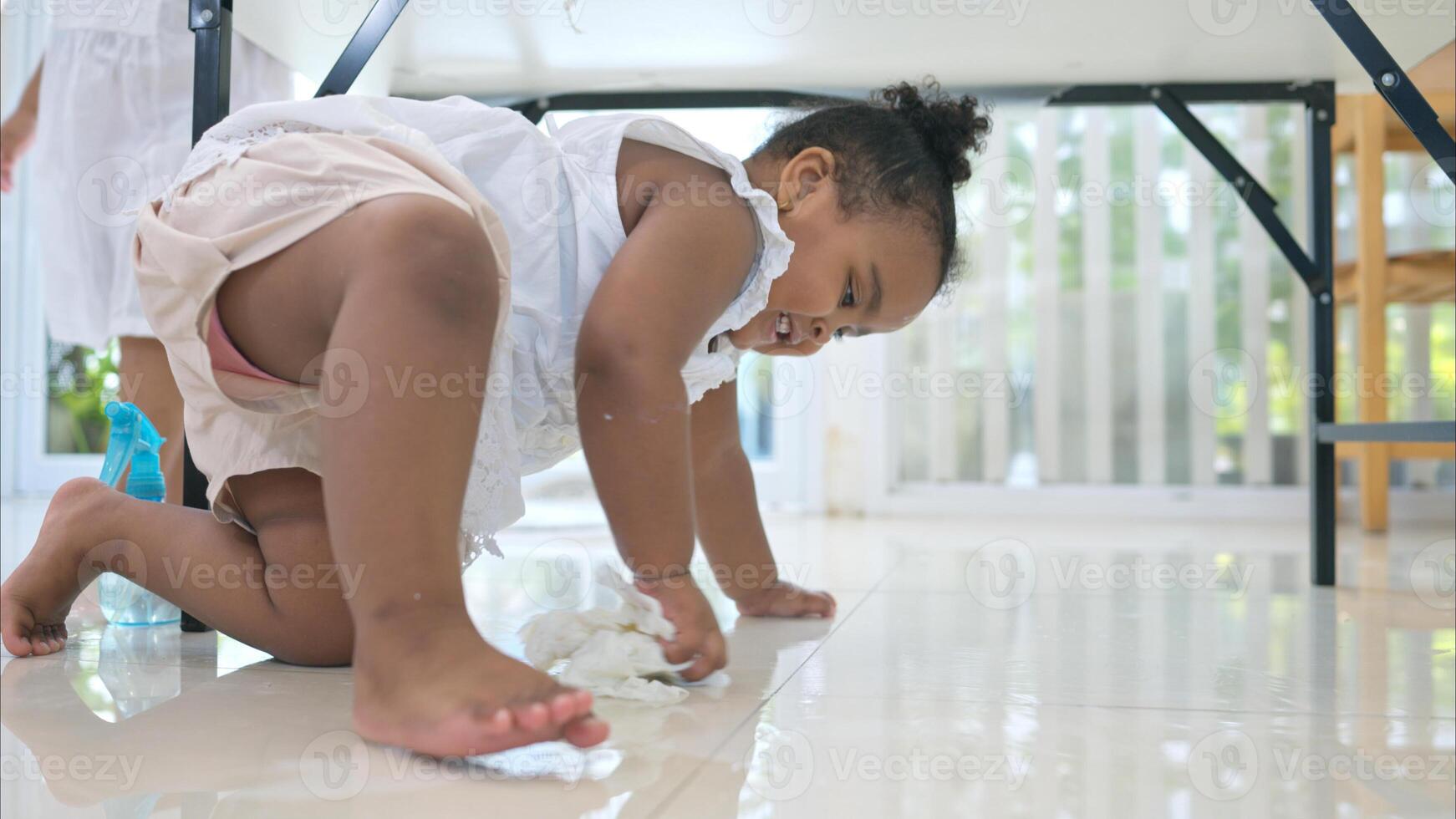 The older sister and younger sister clean the table and floor after glass of milk spilled while drinking photo