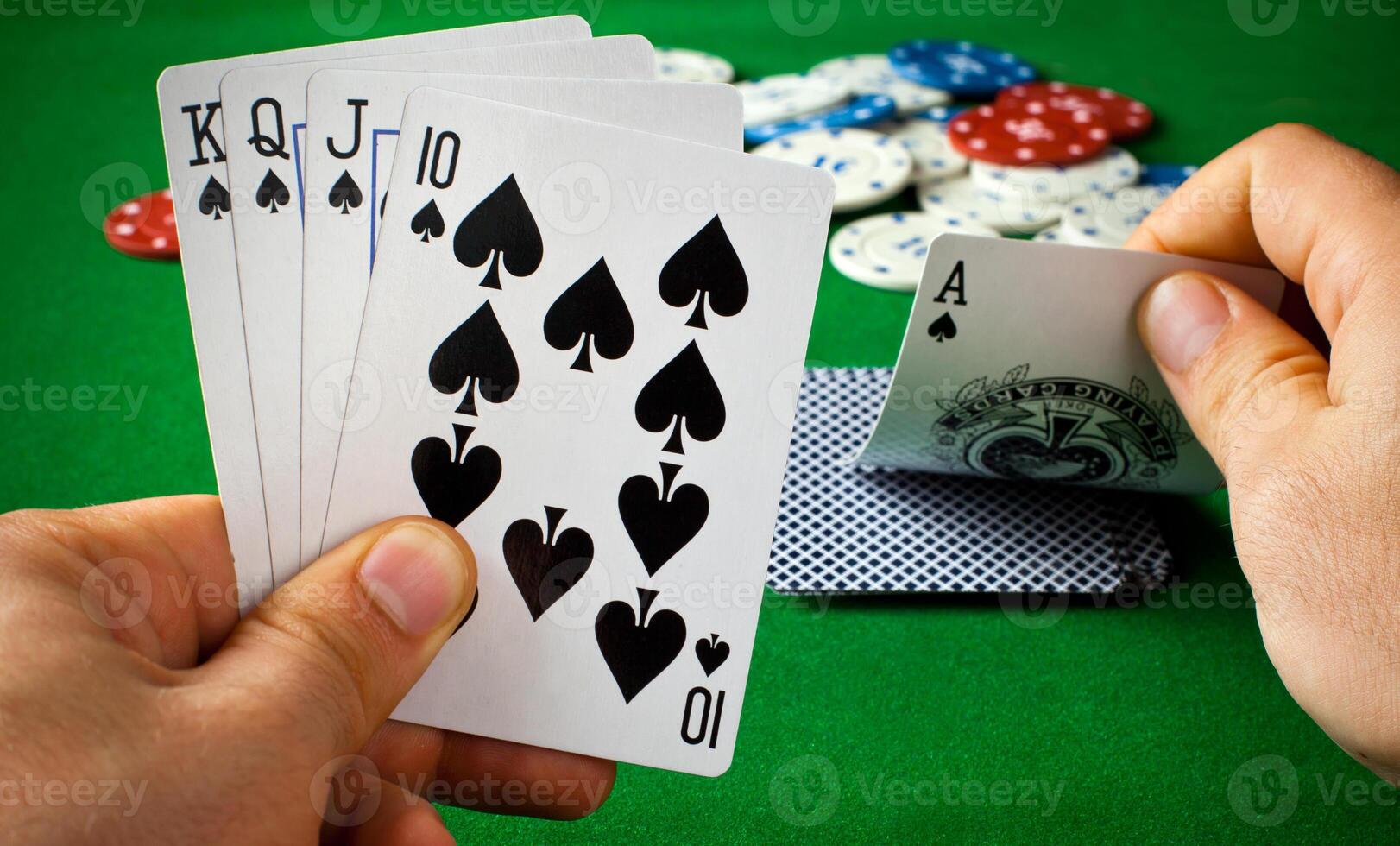 A person holding four cards in front of a green table photo