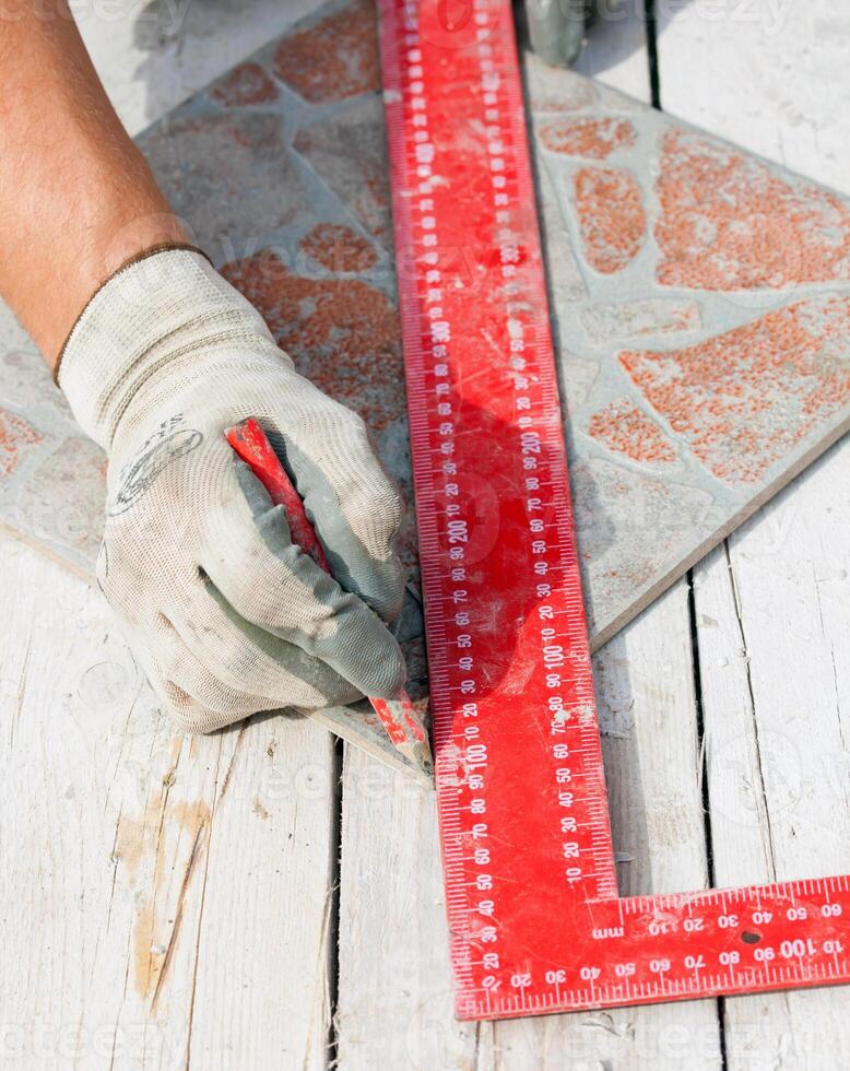 A person is using a ruler to measure a tile photo