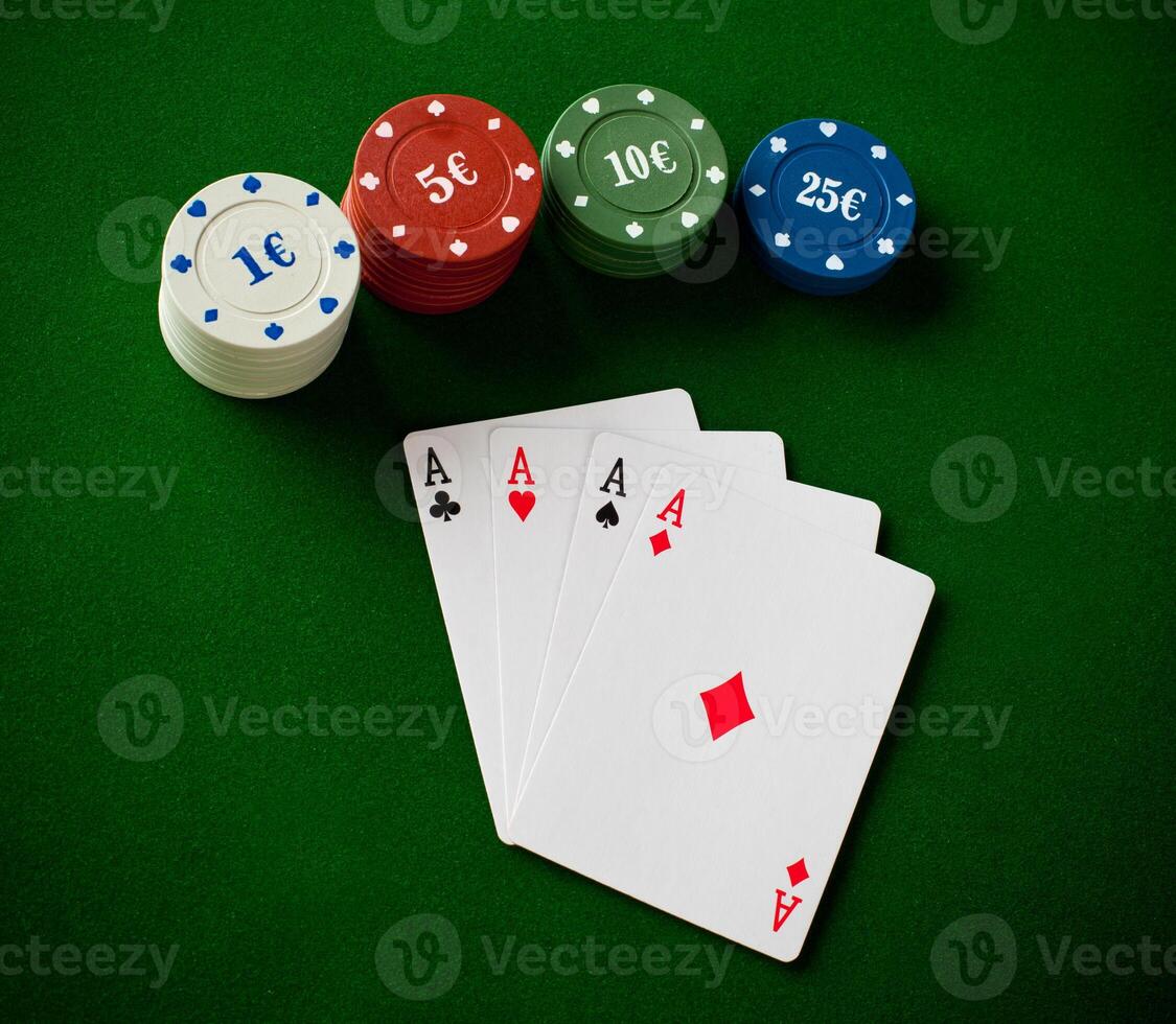 A poker chip, four cards and two chips on a green table photo