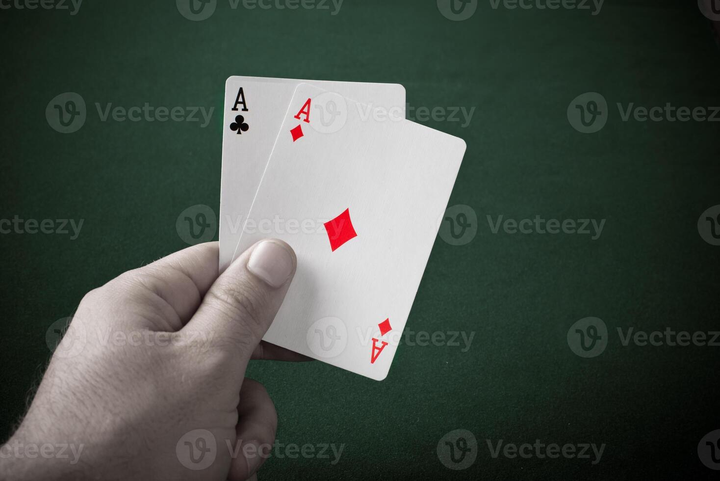 A hand holding two aces on a green table photo