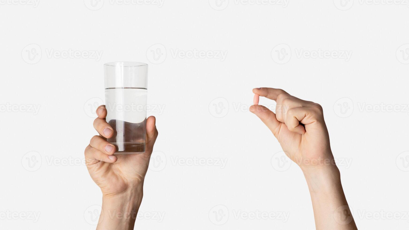 Cropped view of millennial guy holding glass of water and pill on light background, closeup. Panorama photo