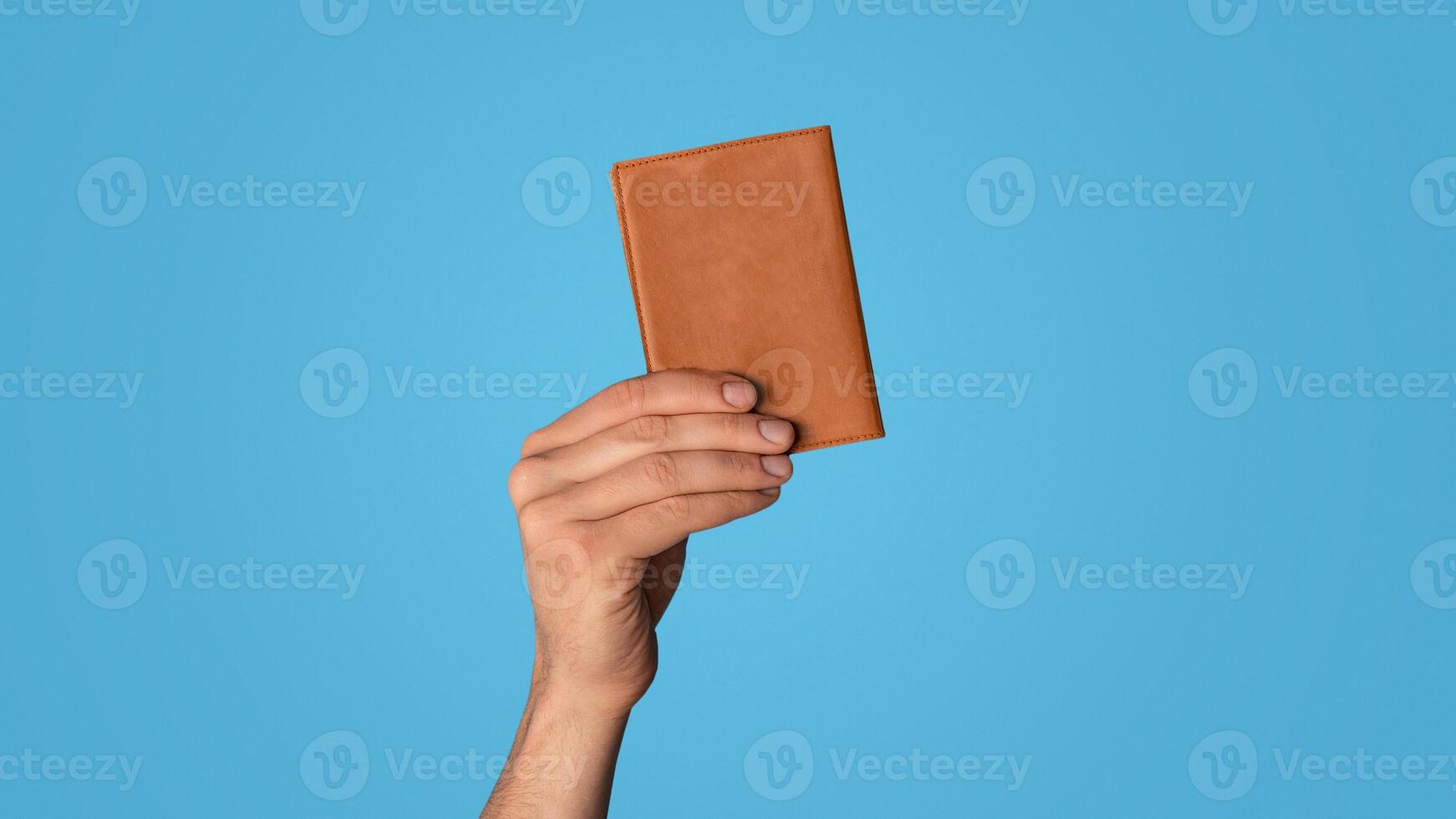 Unrecognizable young guy showing passport on color background, closeup of hand photo