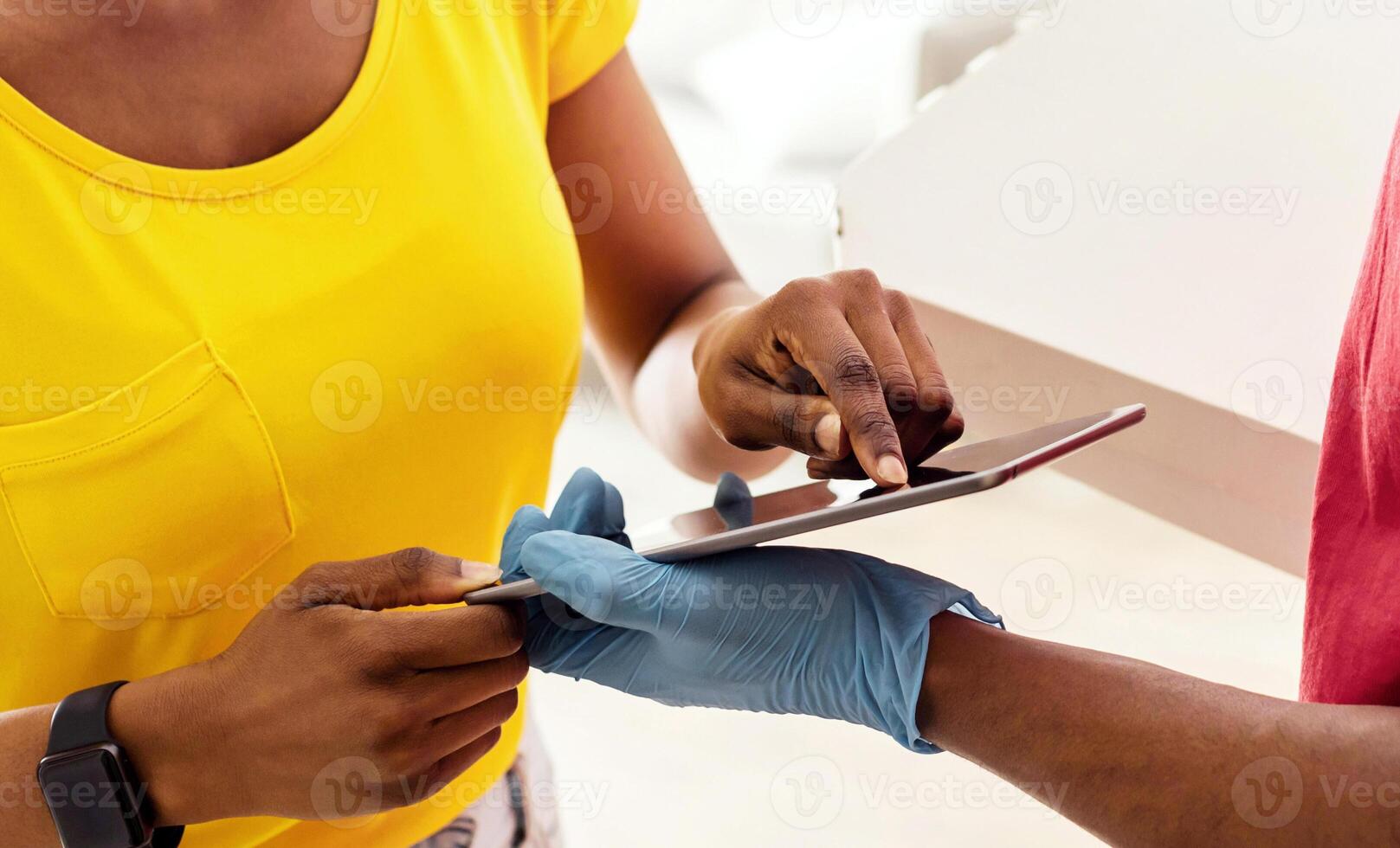 African American Woman Receiving Pizza Box From Deliveryman And Scanning Fingerprint On Tablet Computer For Smart Payment Or Personal Authentification Standing At Home, Wearing Face Mask. Cropped photo
