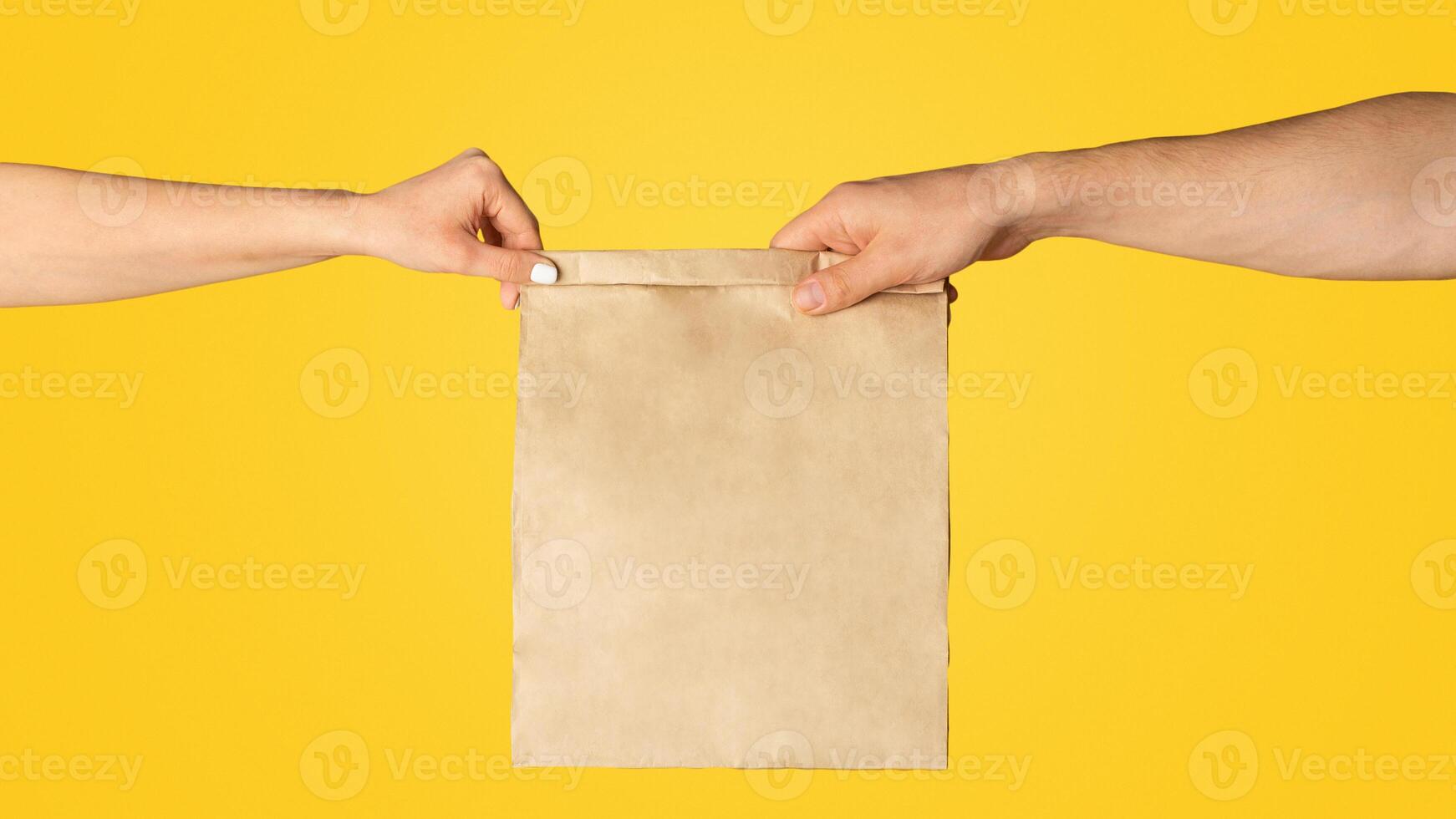 Takeaway food concept. Delivery man giving paper bag with empty space for design to client, orange background photo