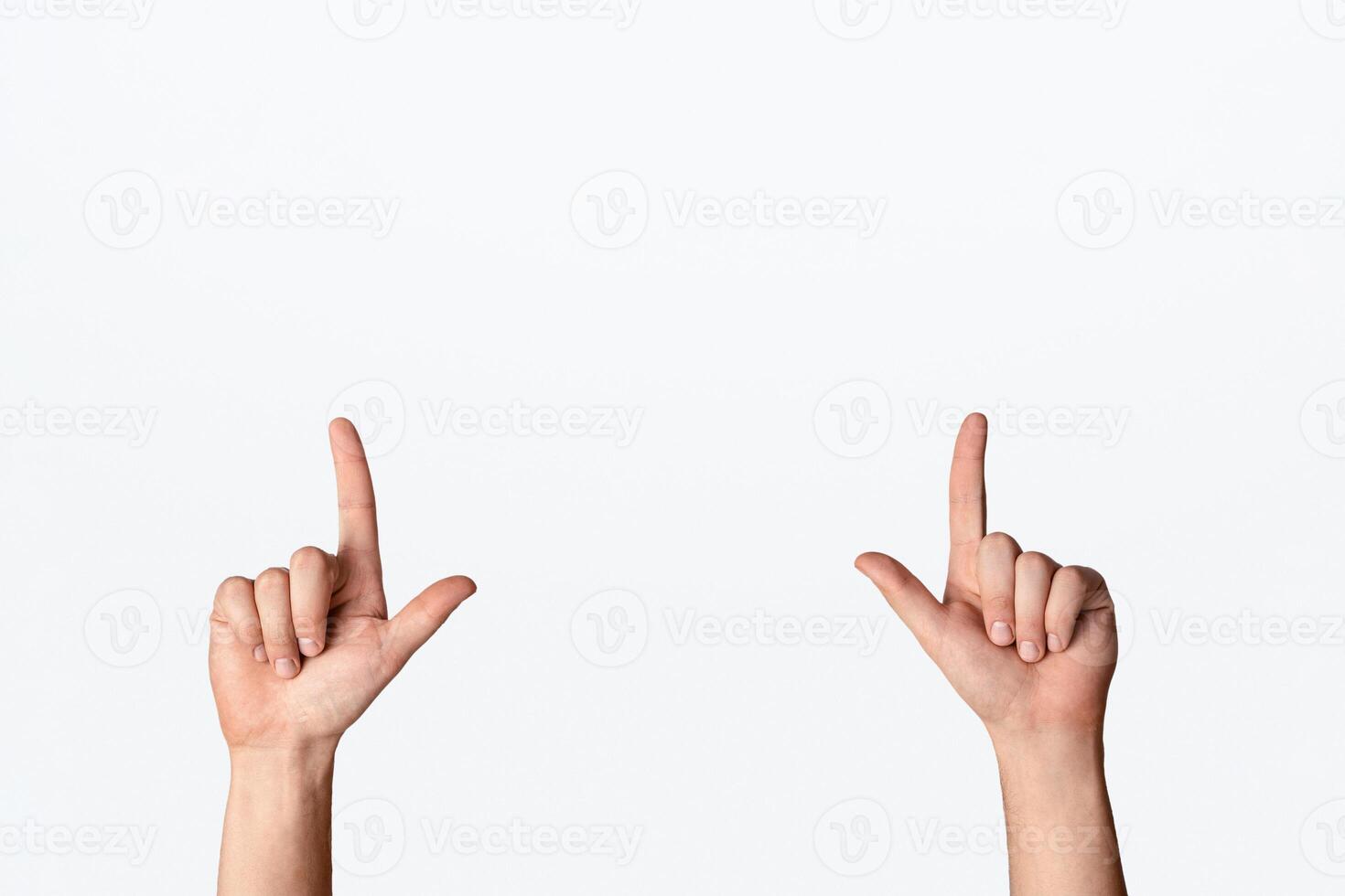 Closeup of young male pointing upwards with both hands on light background, copy space. Panorama photo
