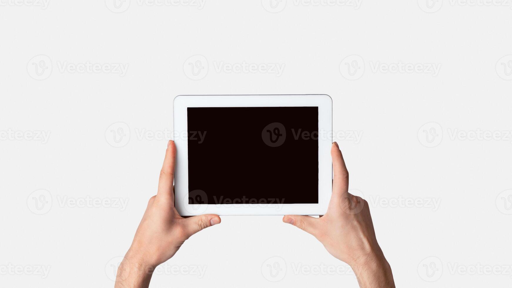 Male hand holding tablet computer on light background, mockup for design. Panorama photo