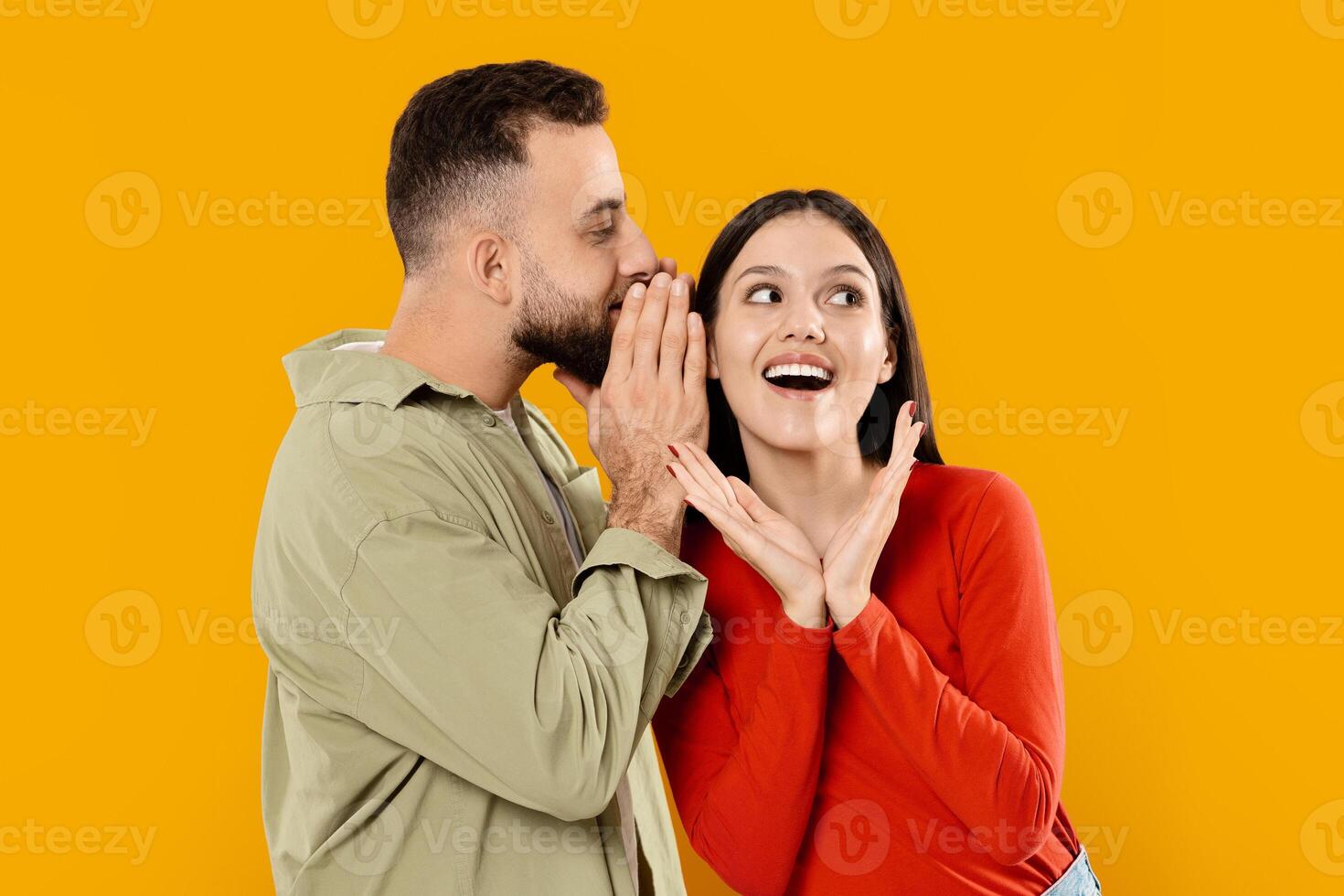 A couple, happily engaged in a playful moment, enjoys each other's company. The man whispers to the woman, who expresses delight, highlighting their love and affection. photo