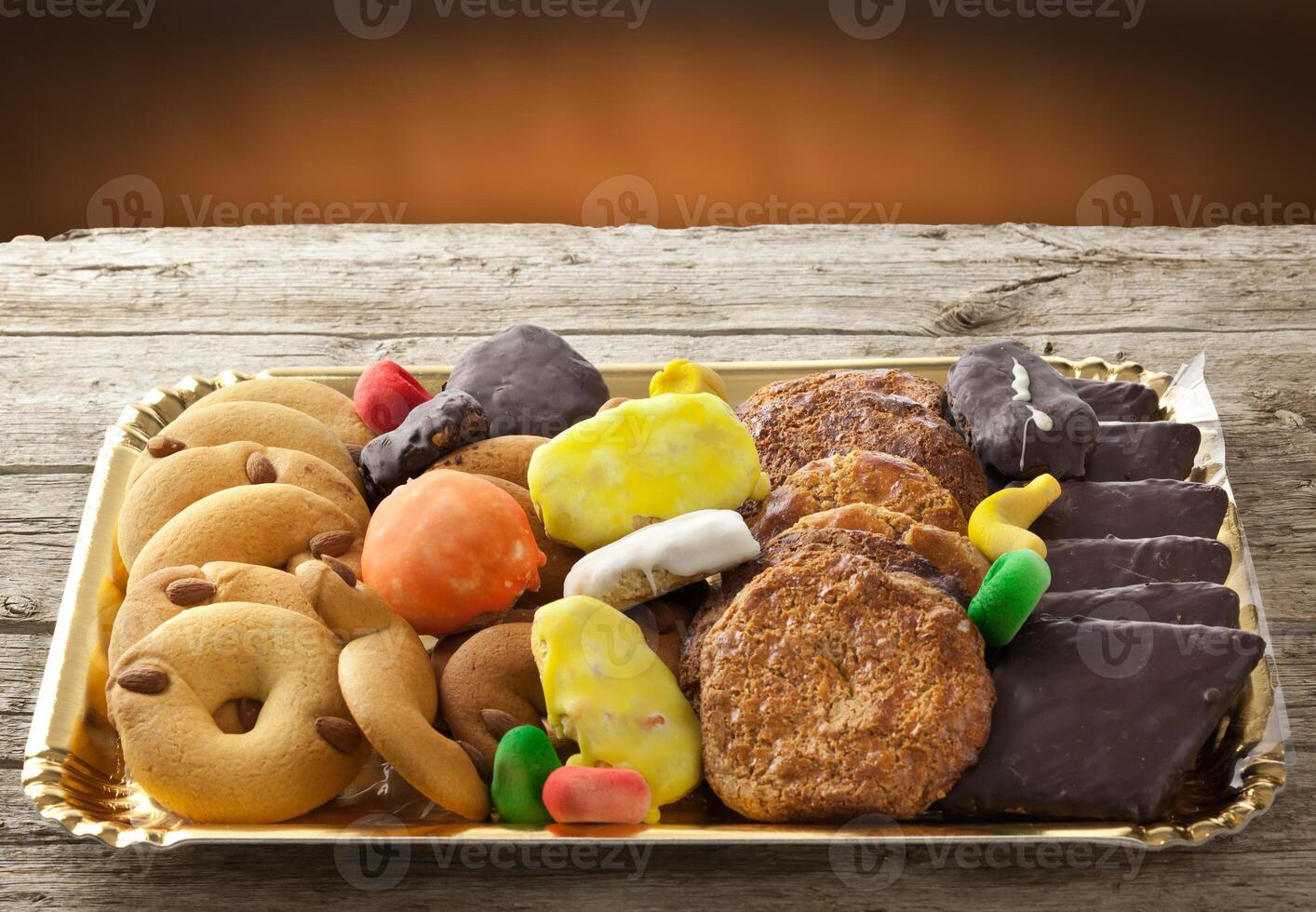 A tray of assorted cookies and candies on a wooden table photo