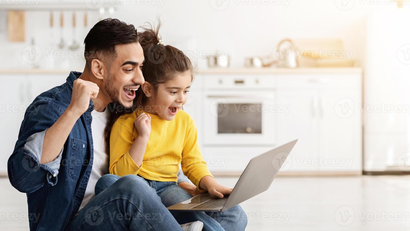 Internet Win. Portrait Of Excited Arab Dad And Daughter With Laptop At Home Celebrating Success, Happy Middle Eastern Family Exclaiming With Joy While Looking At Computer Screen, Panorama photo