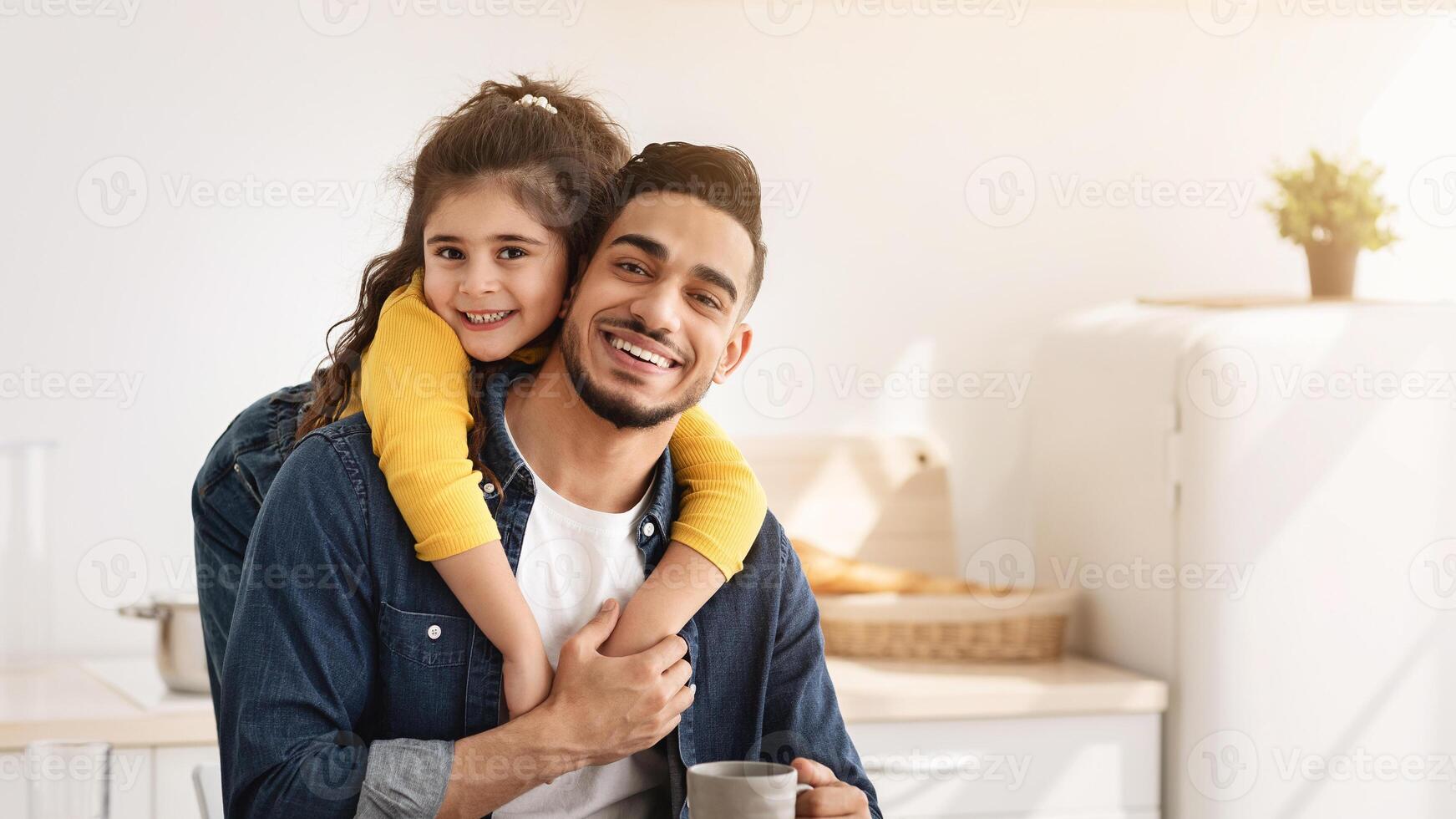 Time With Daddy. Portrait Of Happy Arab Father And Little Daughter Embracing While Having Snacks In Kitchen, Positive Middle Eastern Family Of Two Dad And Female Child Smiling At Camera, Copy Space photo