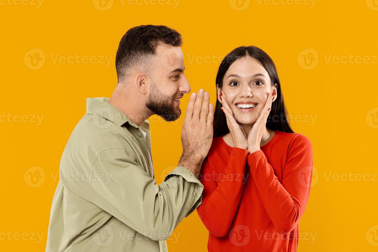 A young couple expresses affection as the man whispers something sweet to the woman. She reacts with surprise and delight, highlighting their playful bond. photo
