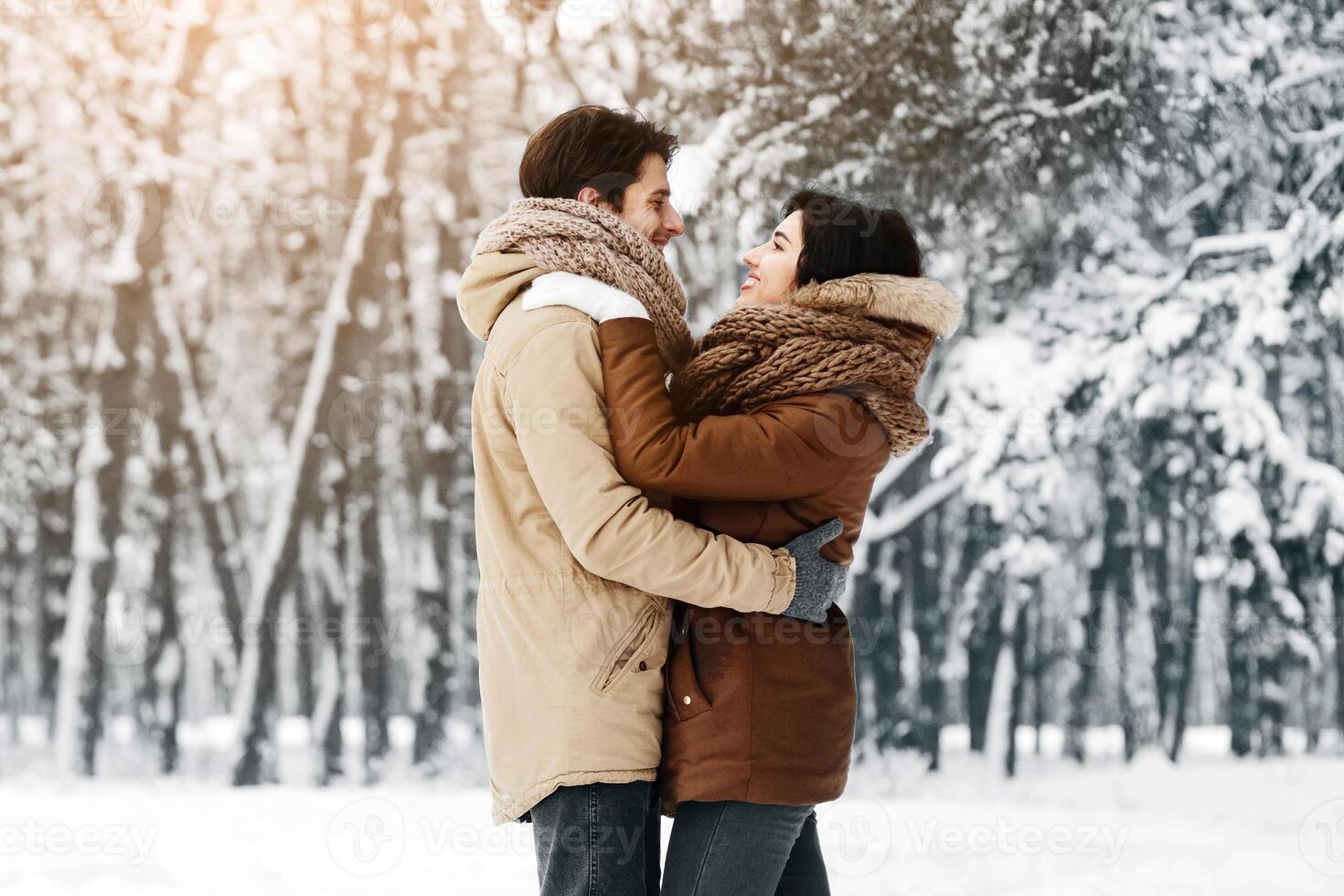 Christmas Romance. Loving Couple Embracing Standing In Snowy Winter Forest Or Park In The Morning. Empty Space For Text photo