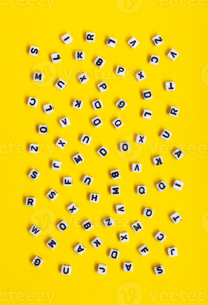 White cubes with letters scattered randomly on a yellow background. photo