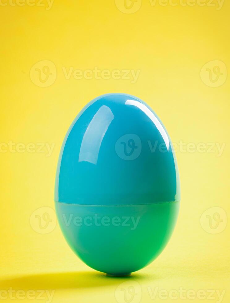 Blue plastic egg close up on yellow background photo