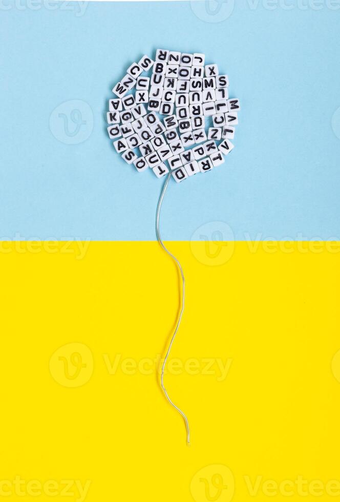 Balloon made of letters on a yellow and blue background. Conceptual image regarding literature, language and freedom of expression. photo