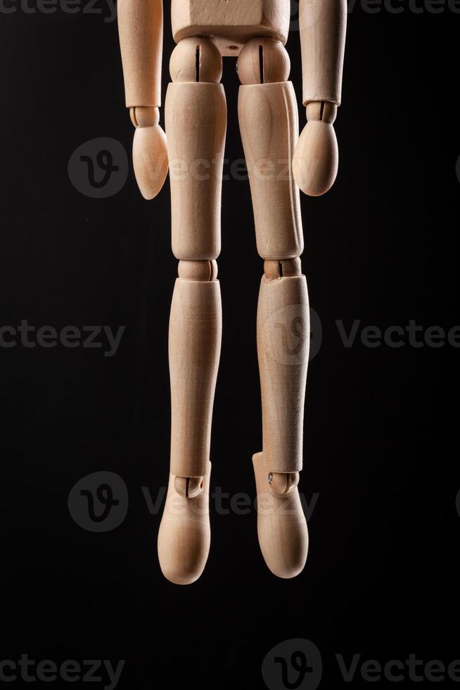 Wood figure hanged with a rope Isolated on black background. photo
