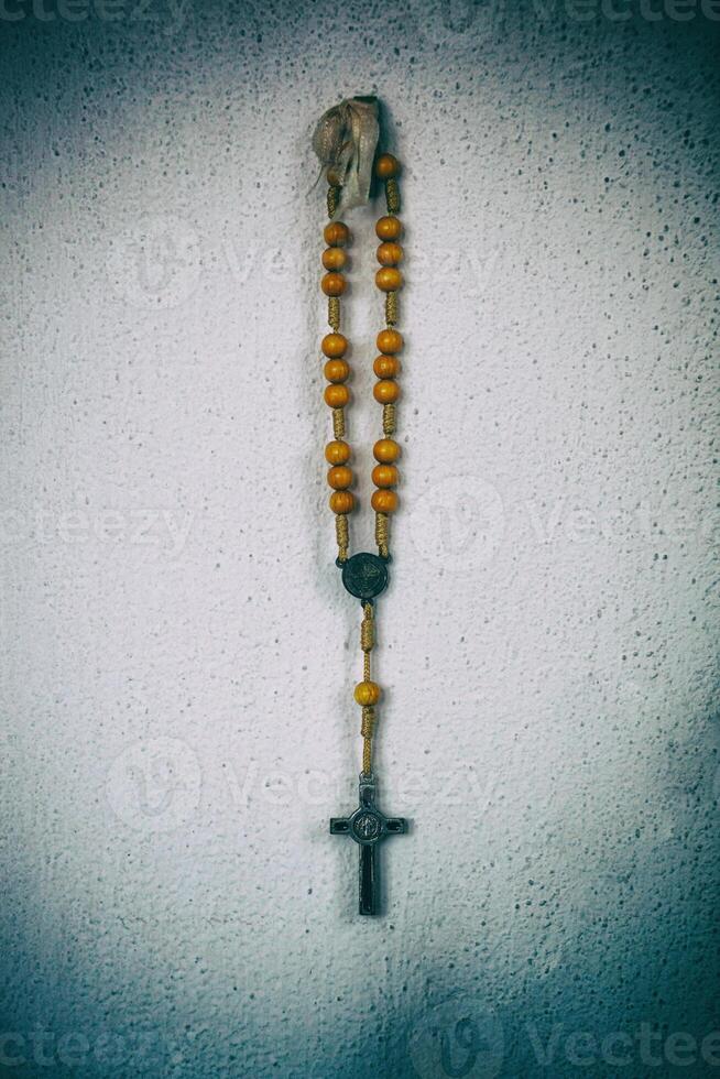 Rosary hanging on the wall with grunge filter and vignetting. Religious conceptual image. photo