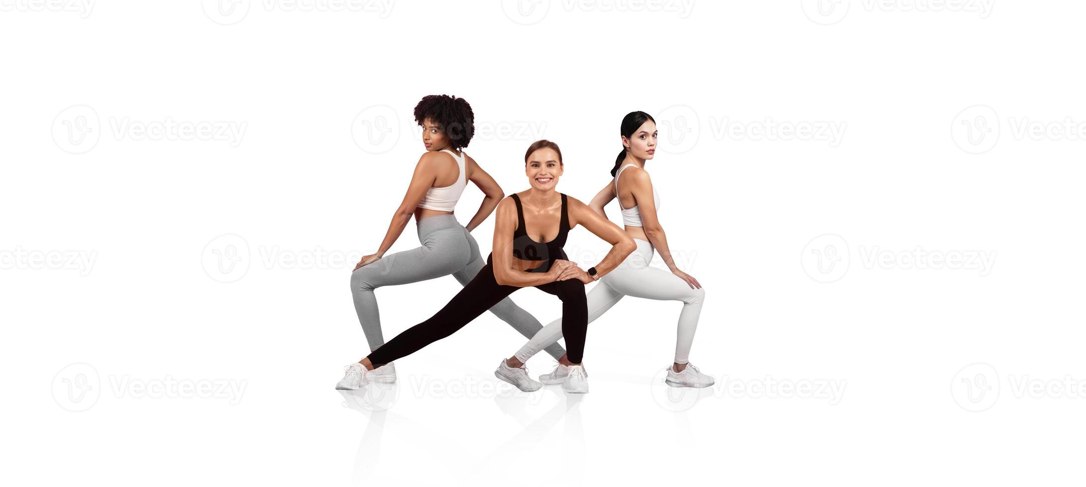 Three women showcase dynamic workout poses indoors, dressed in trendy fitness apparel. Their confident postures and expressions emphasize strength and determination during their exercise routine. photo
