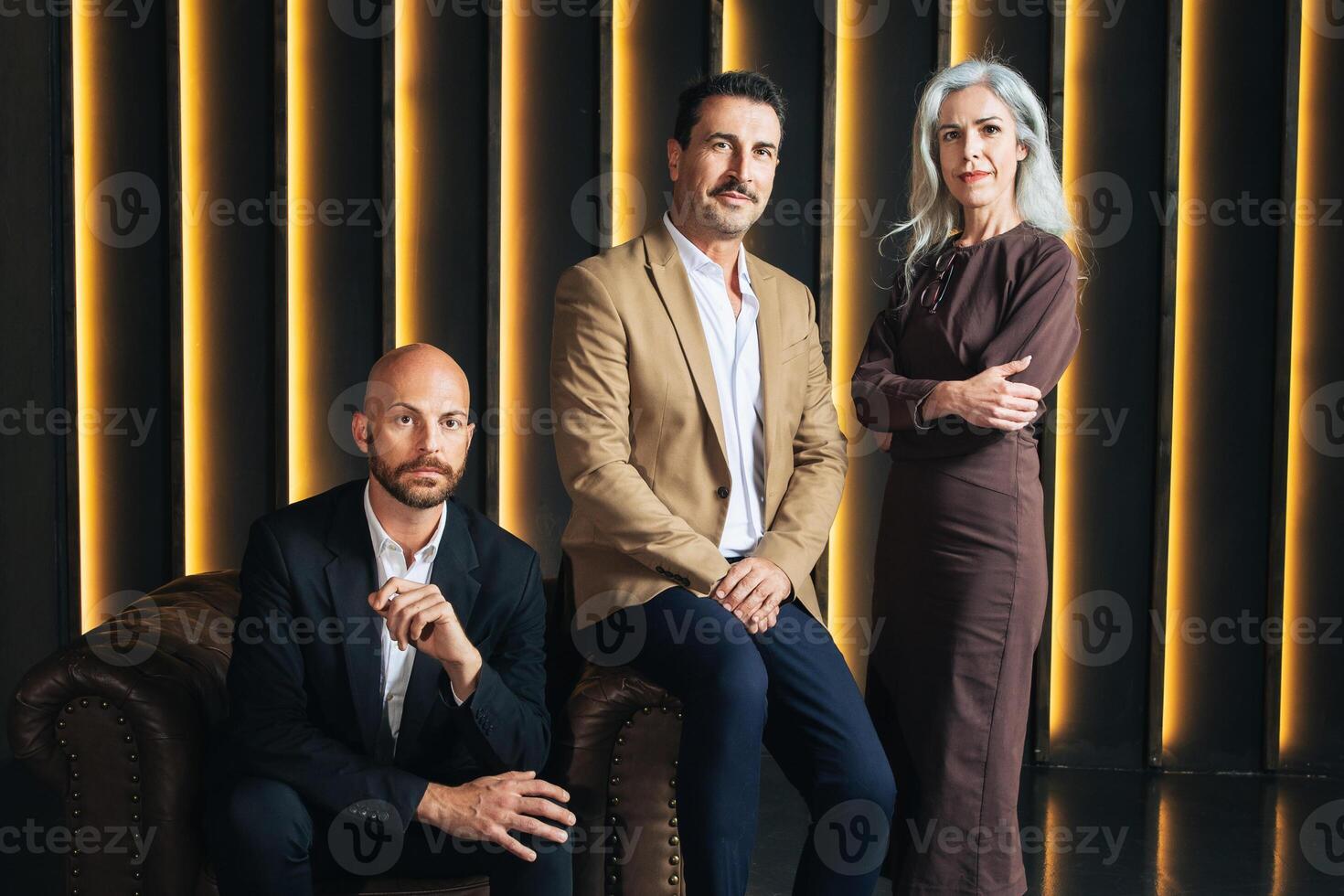In a contemporary office, three European business professionals pose confidently. They represent leadership roles, showcasing a collaborative and innovative corporate atmosphere. photo