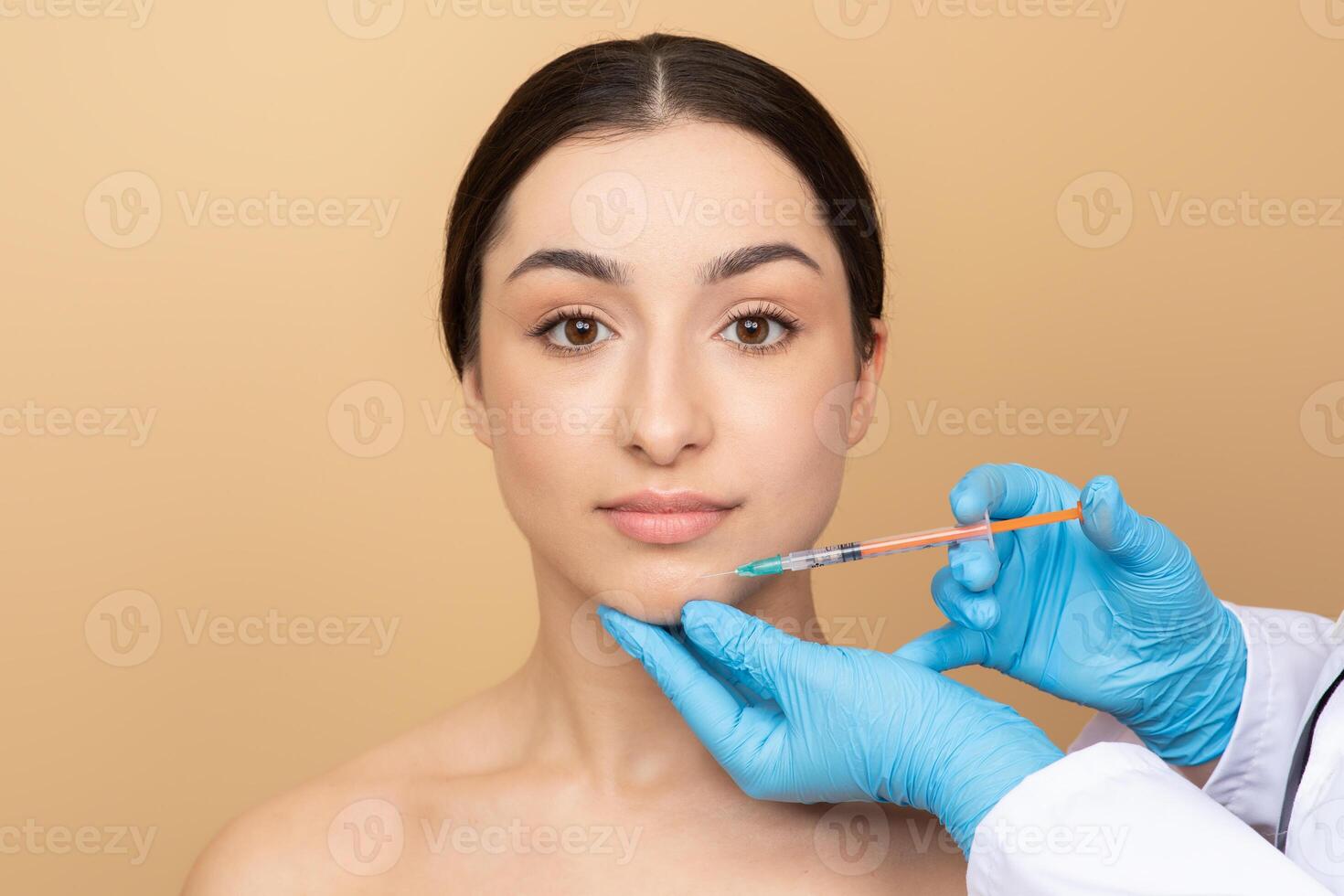 A brunette woman in her twenties is pampering herself with a skincare procedure. She sits calmly, focusing on her beauty treatment while a professional applies the product gently. photo